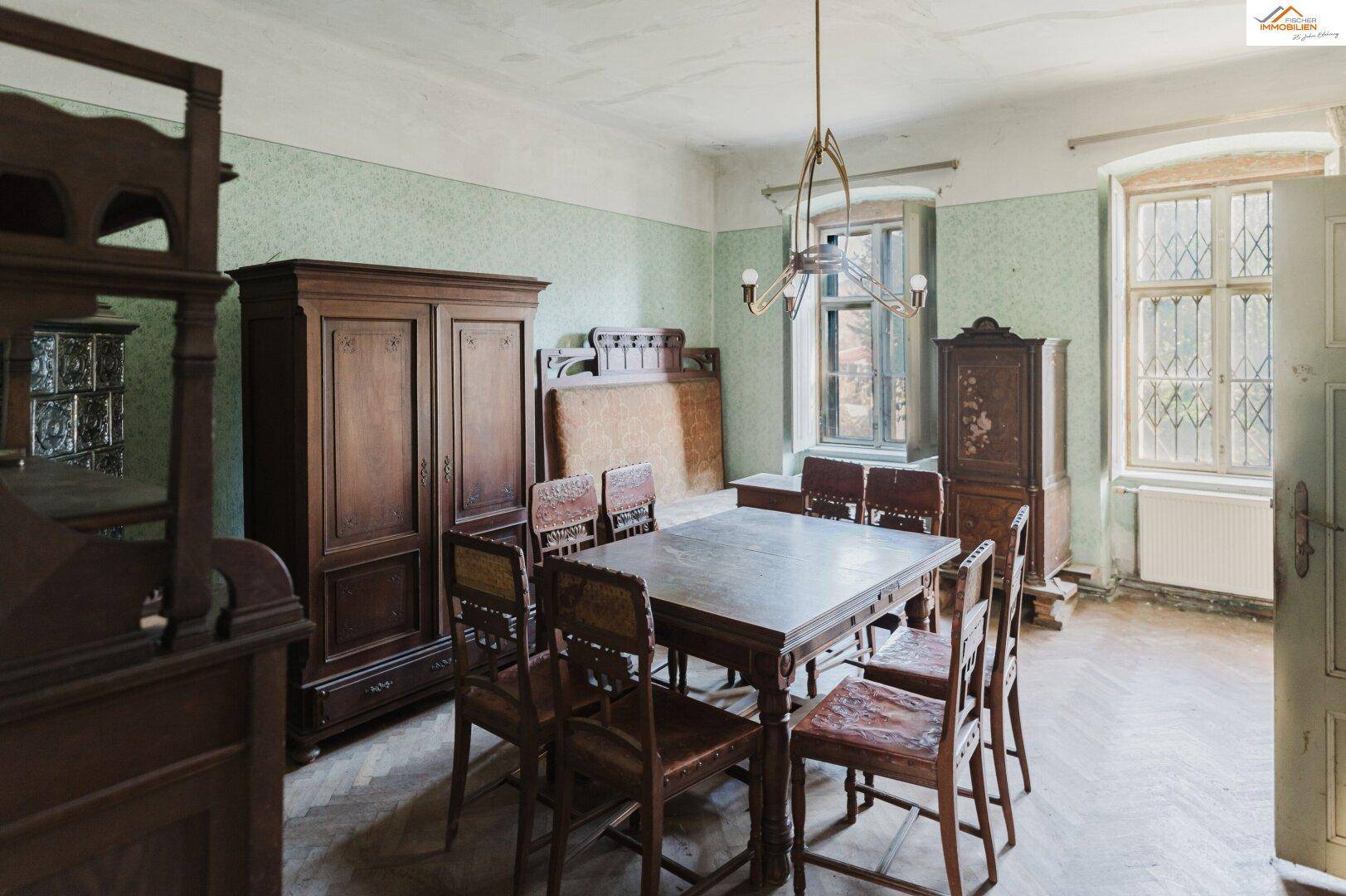 Esszimmer mit antiken Holzmöbeln, einem großen Esstisch und Blick ins Grüne.