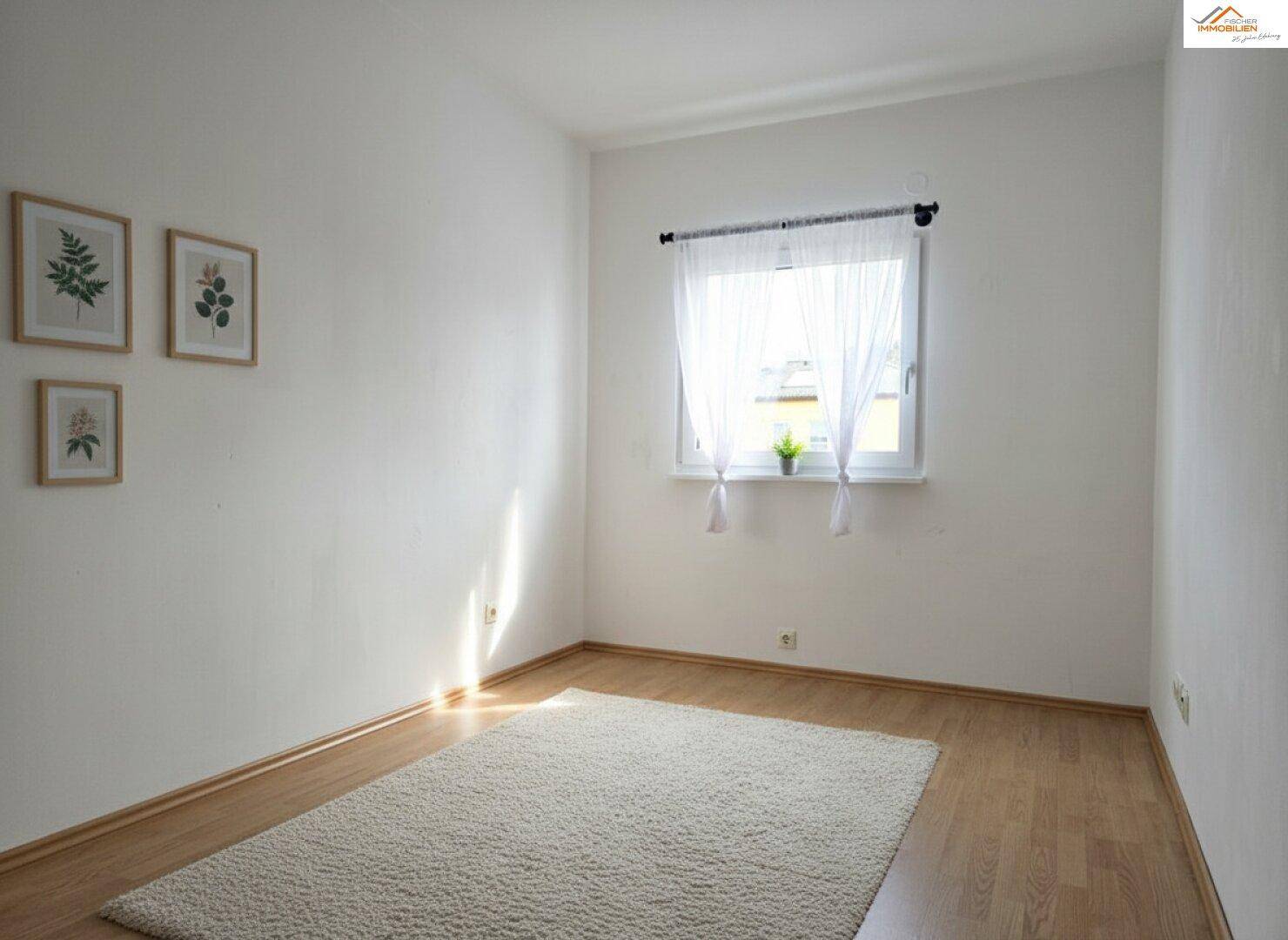 Schlichter Raum mit Laminatboden und weißen Wänden, gut beleuchtet durch ein Fenster.