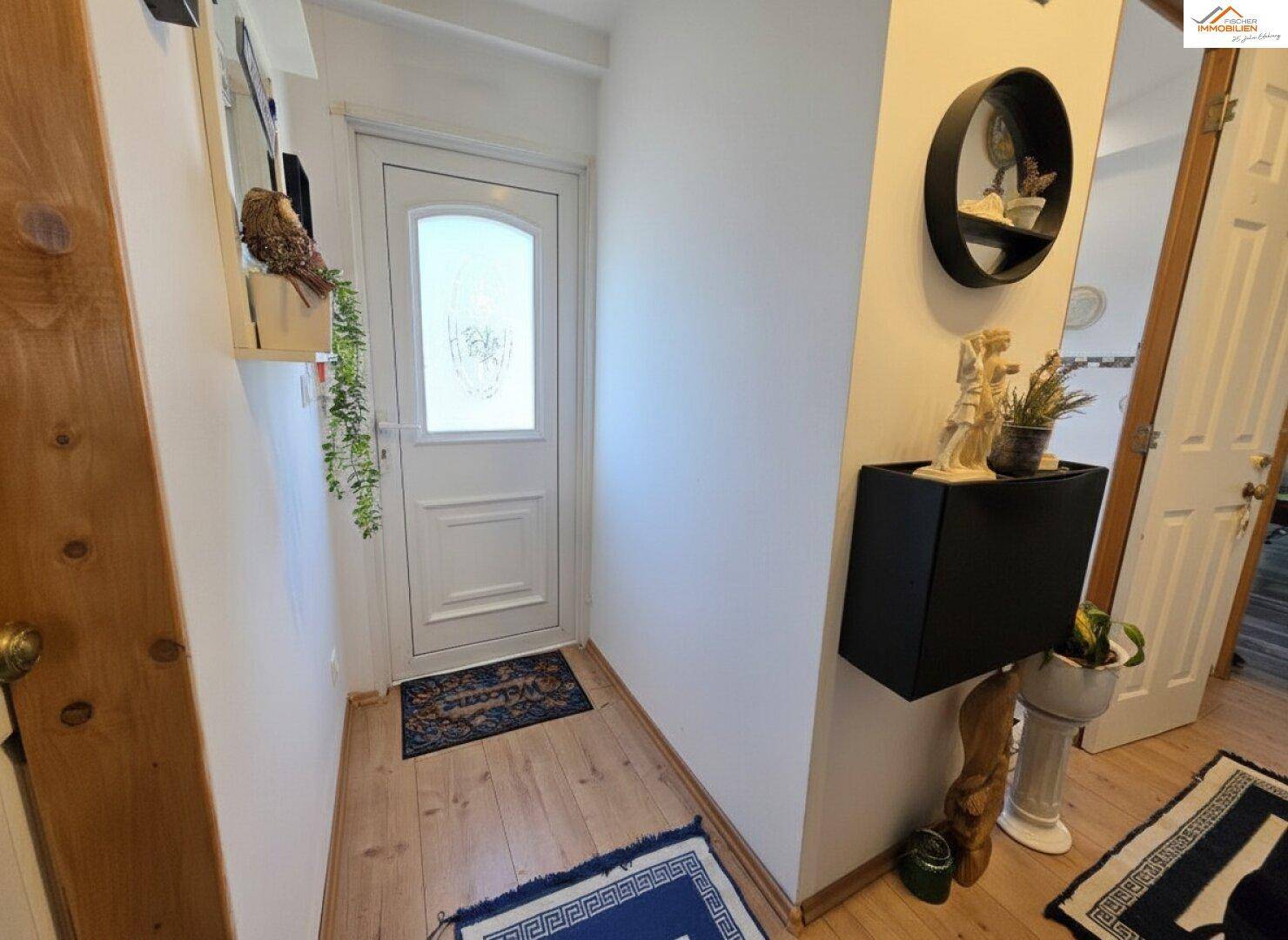 Heller Eingangsbereich mit Holzboden und einer modernen schwarzen Konsole.