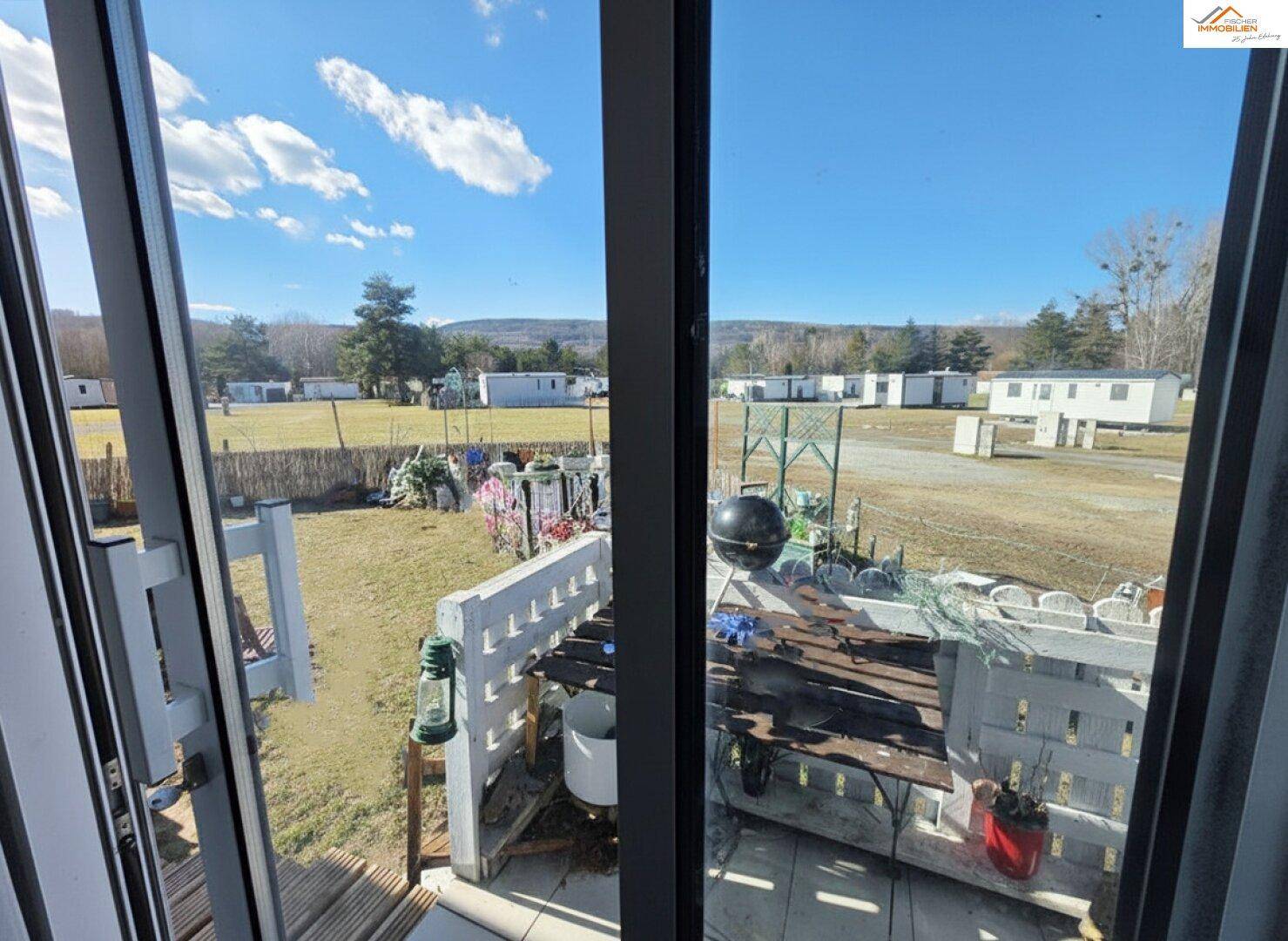 Blick aus dem Fenster auf die umliegende Landschaft mit weiteren Mobilheimen.