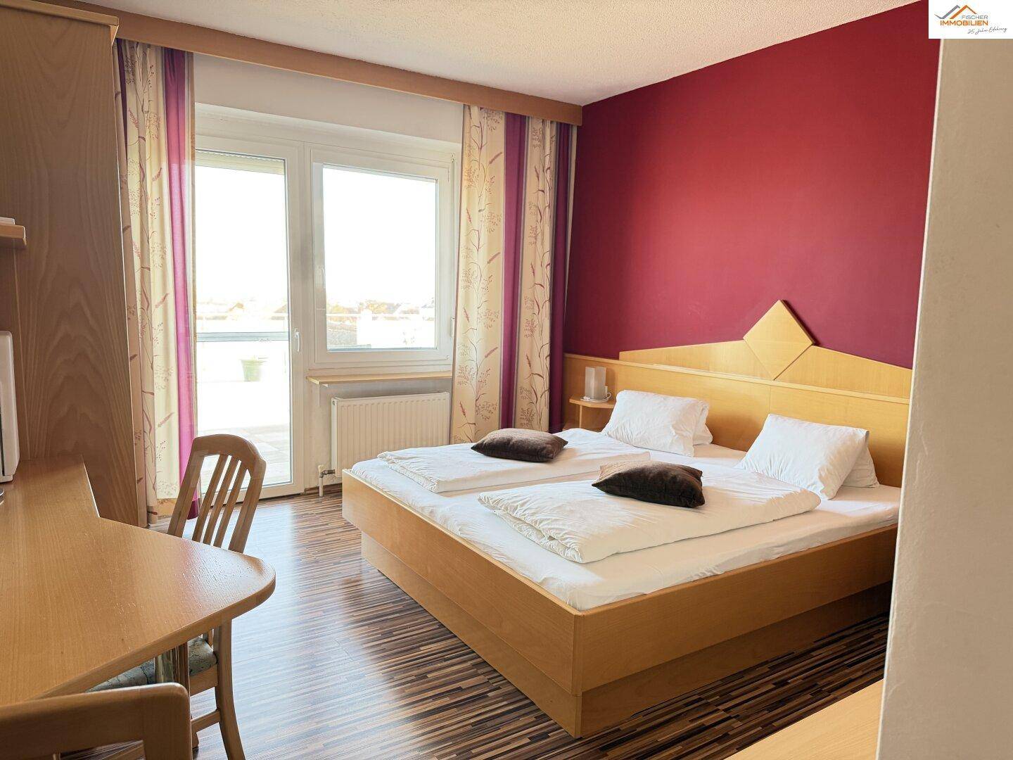 Gemütliches Schlafzimmer mit Doppelbett, Holzboden und Zugang zum Balkon.