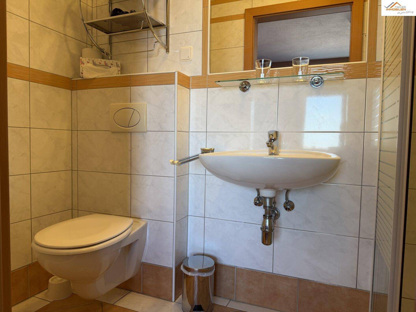 Modernes WC mit Waschbecken und Wand-WC, gefliest in hellen Farben.