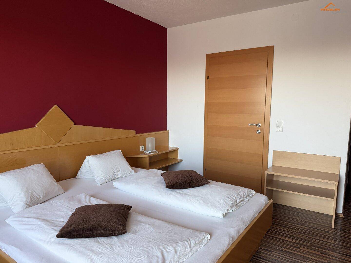 Komfortables Schlafzimmer mit Doppelbett, Holzboden und schlichter Einrichtung.