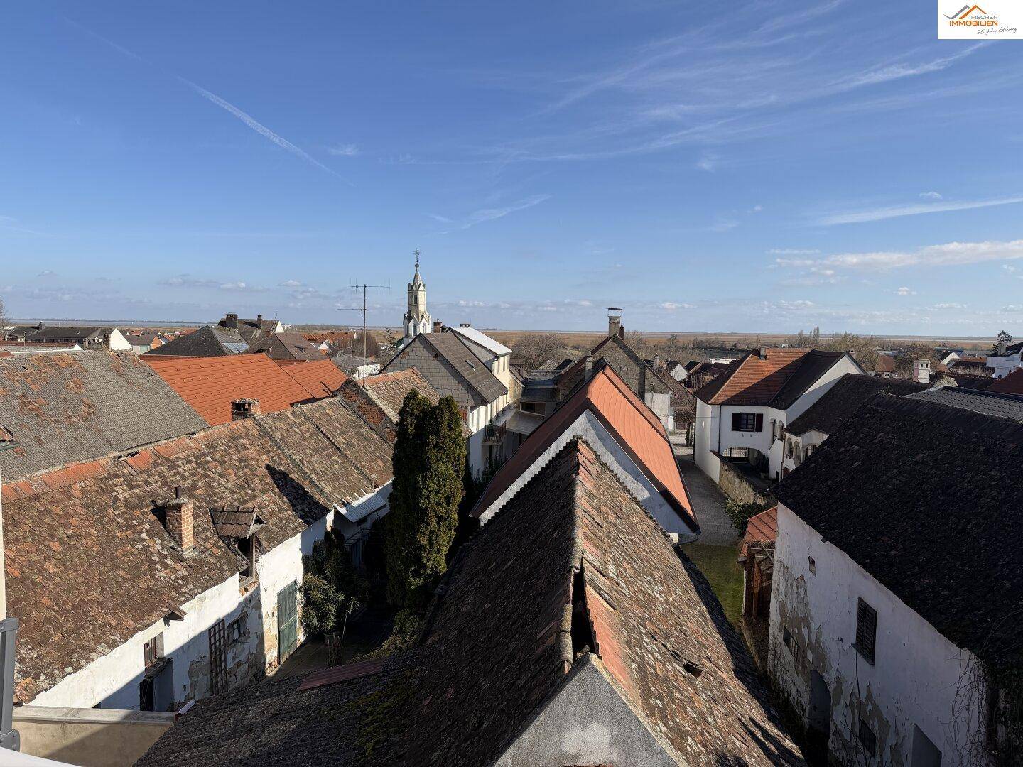 Weitblick über die Dächer der Stadt mit einem Kirchturm im Hintergrund.