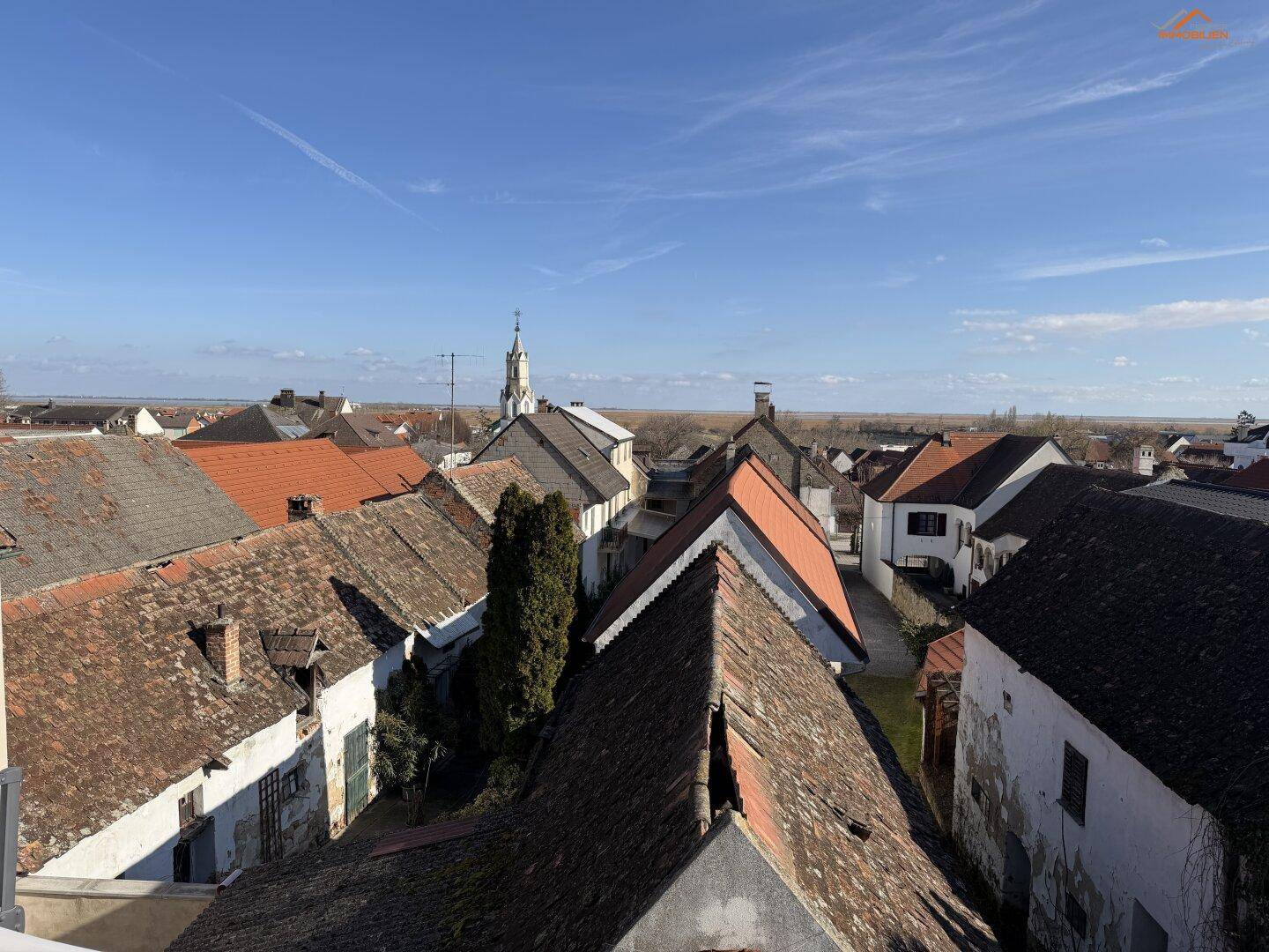 Weitläufiger Blick über die Dächer der Stadt mit einem Kirchturm in der Ferne.