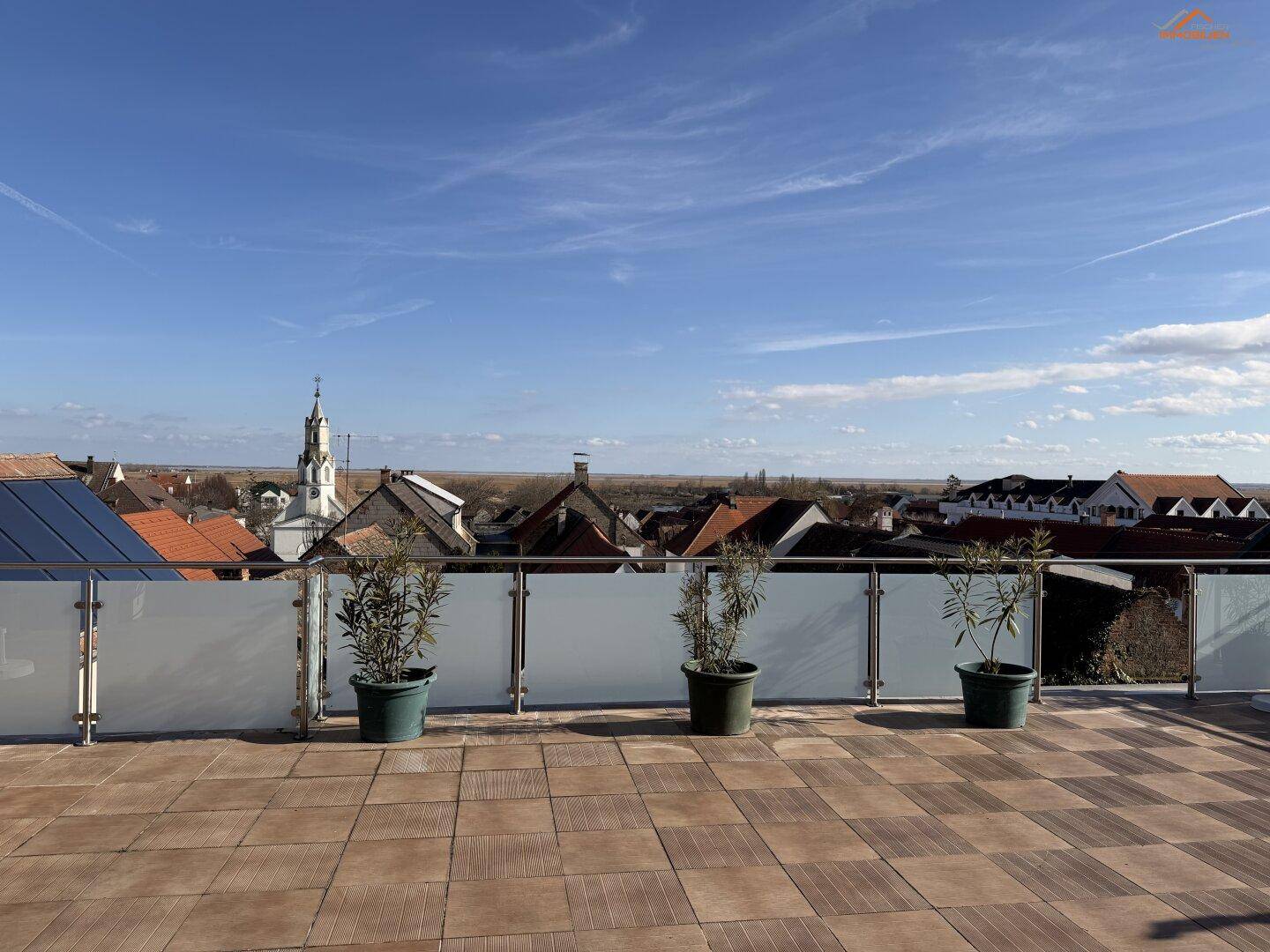 Große Dachterrasse mit Fliesenboden, Pflanzen und weitem Blick über die Umgebung.
