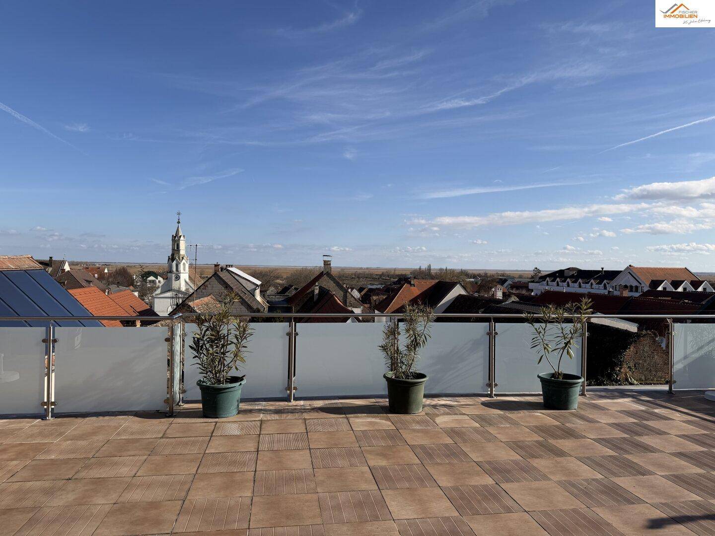 Geräumige Dachterrasse mit Fliesenboden, Pflanzen und weitem Blick über die Umgebung.