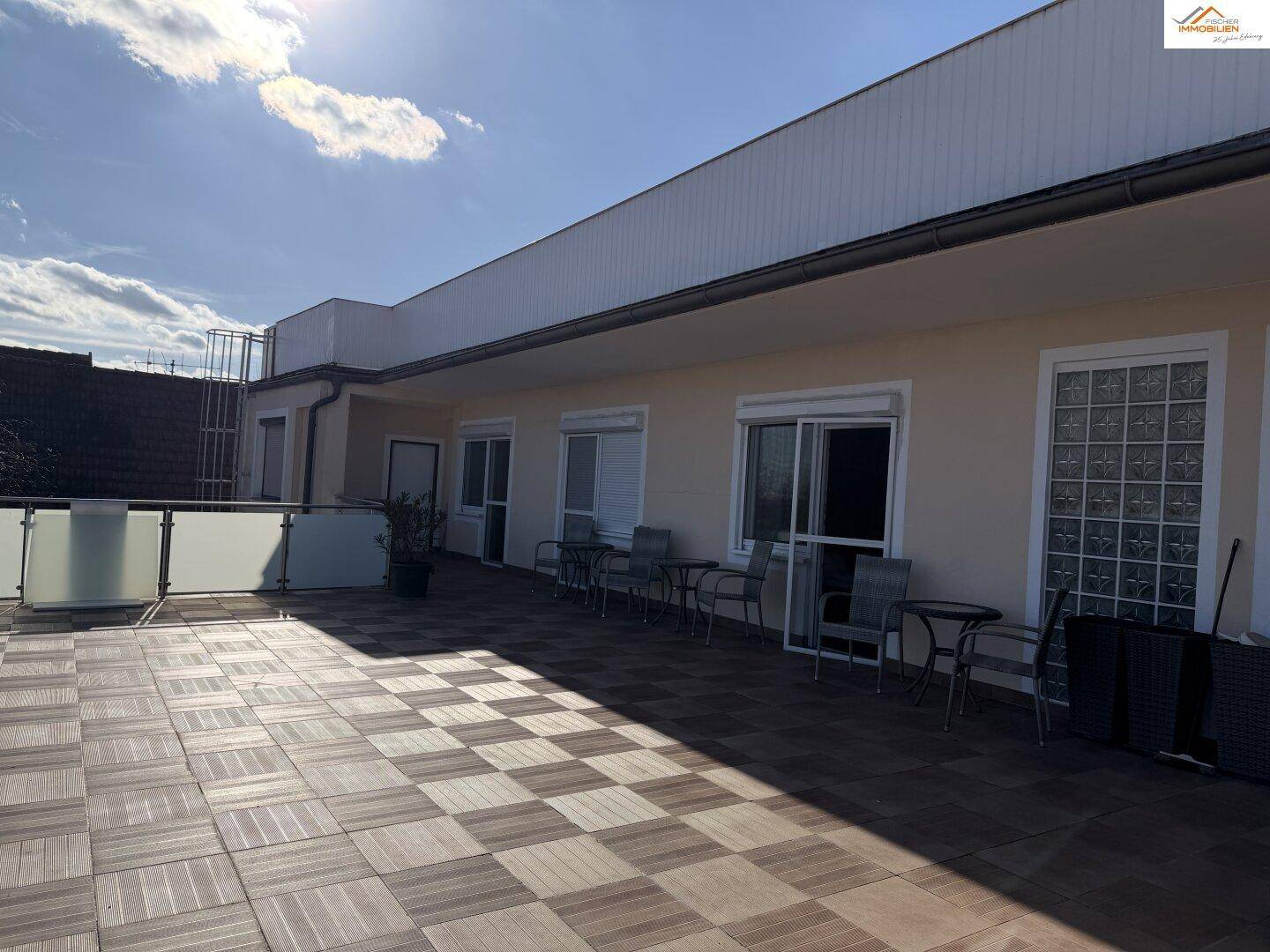 Sonnige Dachterrasse mit Sitzgelegenheiten und Zugang zu mehreren Zimmern.
