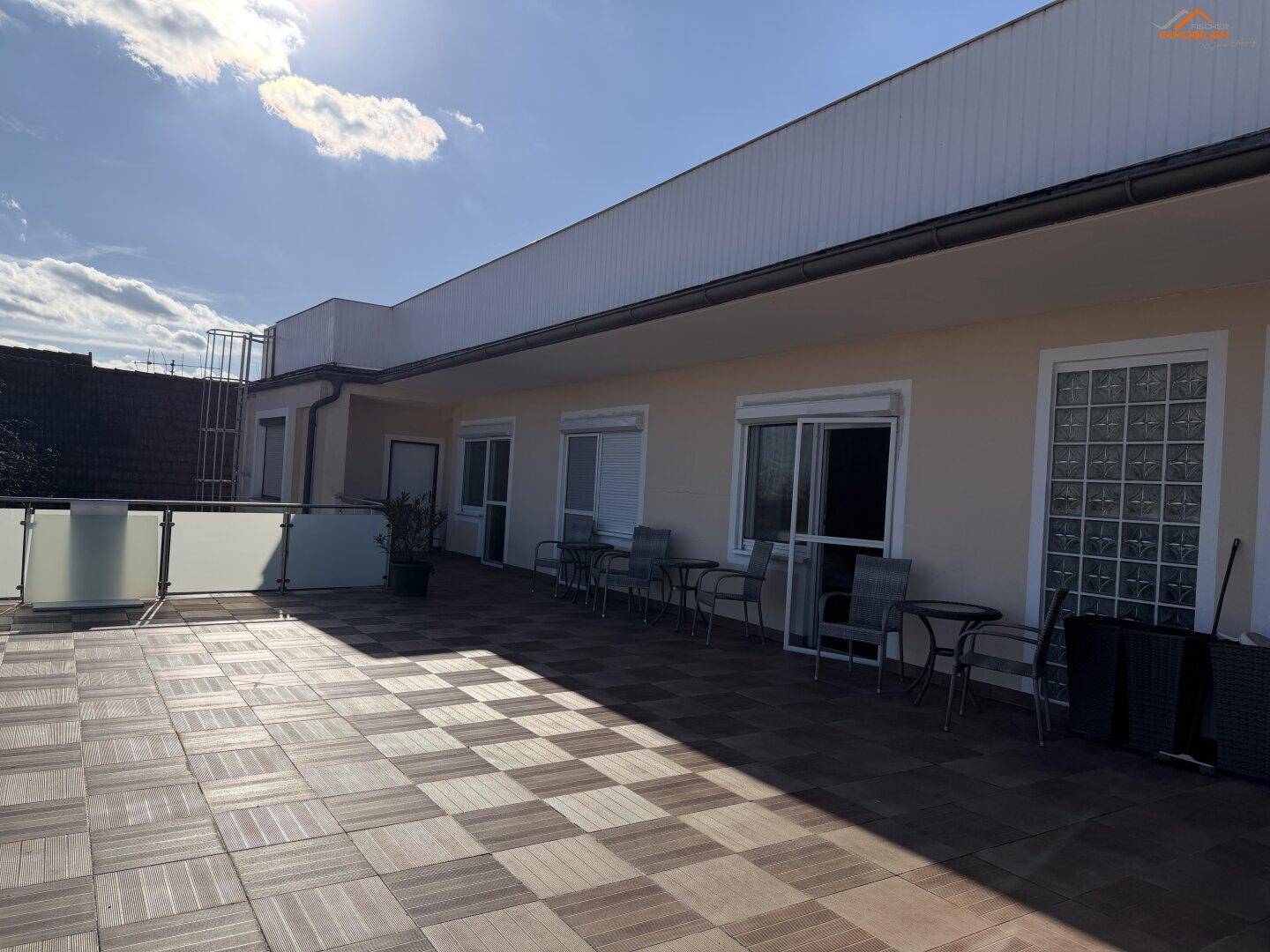 Sonnige Dachterrasse mit Sitzgelegenheiten und Blick auf die umliegenden Gebäude.