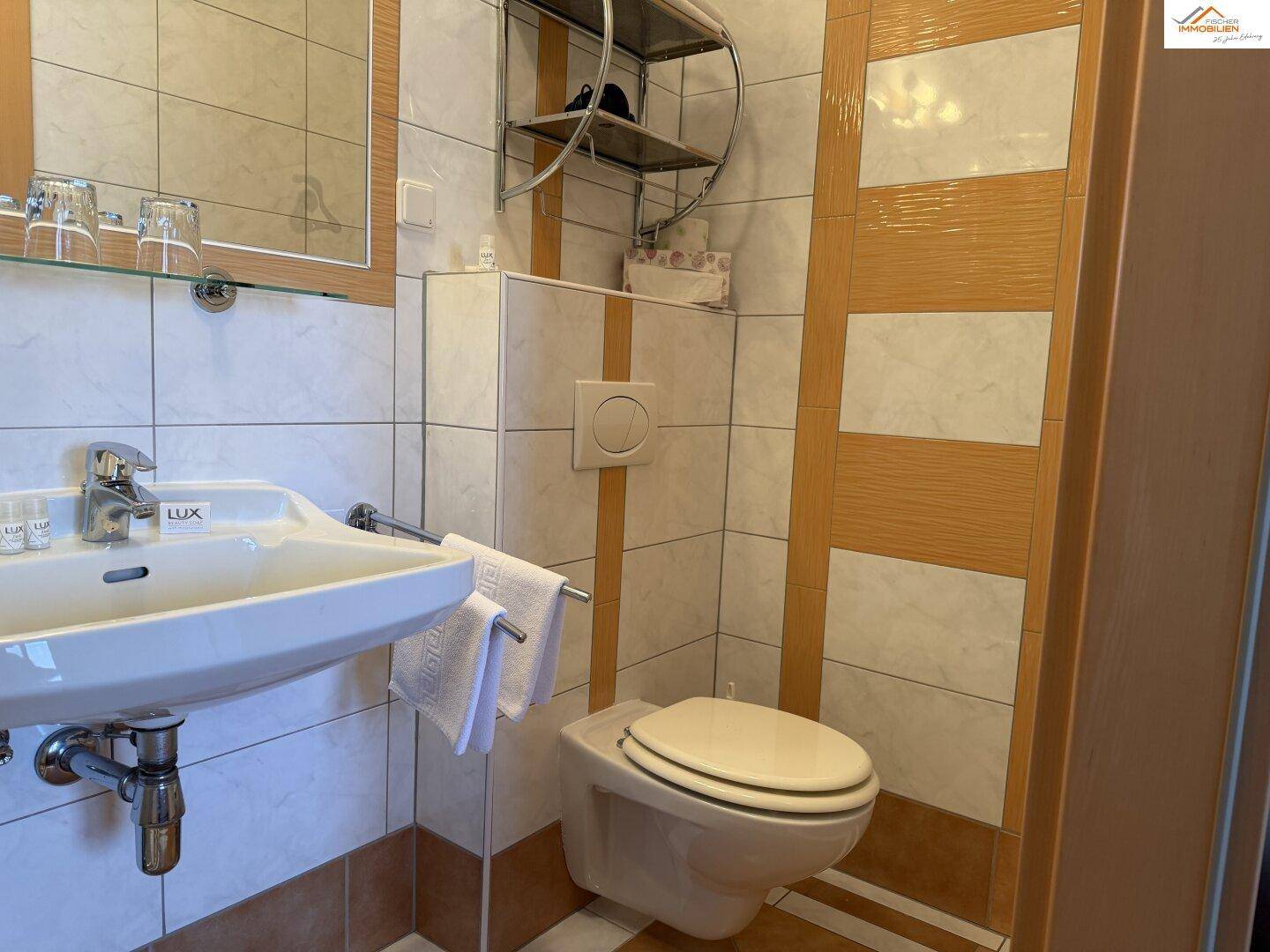 Kleines WC mit Waschbecken und Wand-WC, gefliest in hellen Farben.