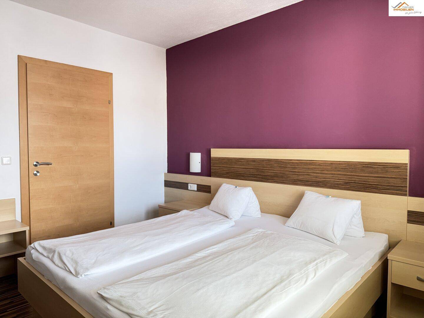 Schlafzimmer mit Doppelbett, Holzboden und moderner Einrichtung.