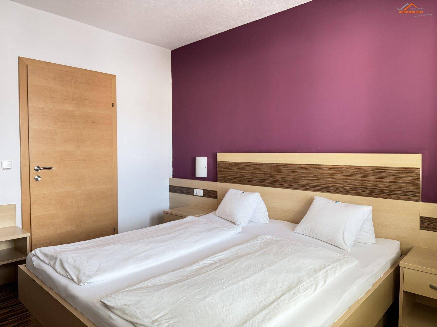 Gemütliches Schlafzimmer mit Doppelbett, Holzboden und farbiger Akzentwand.