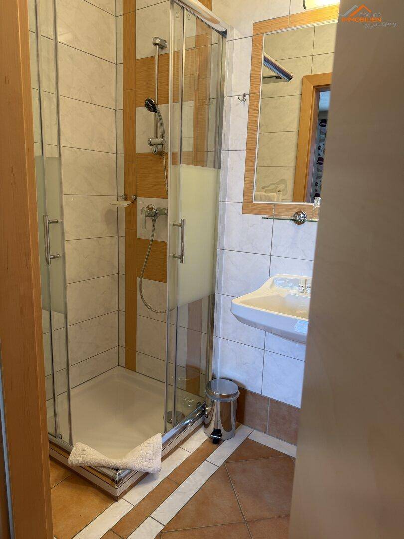 Modernes Badezimmer mit Duschkabine, Waschbecken und hellen Fliesen.