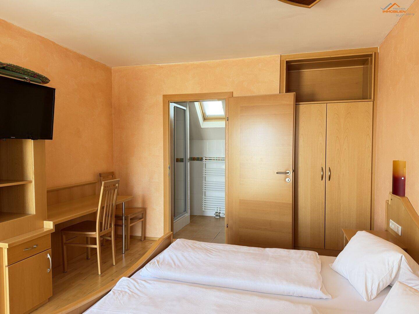 Gemütliches Schlafzimmer mit Doppelbett, Holzmöbeln und Zugang zu einem Badezimmer.
