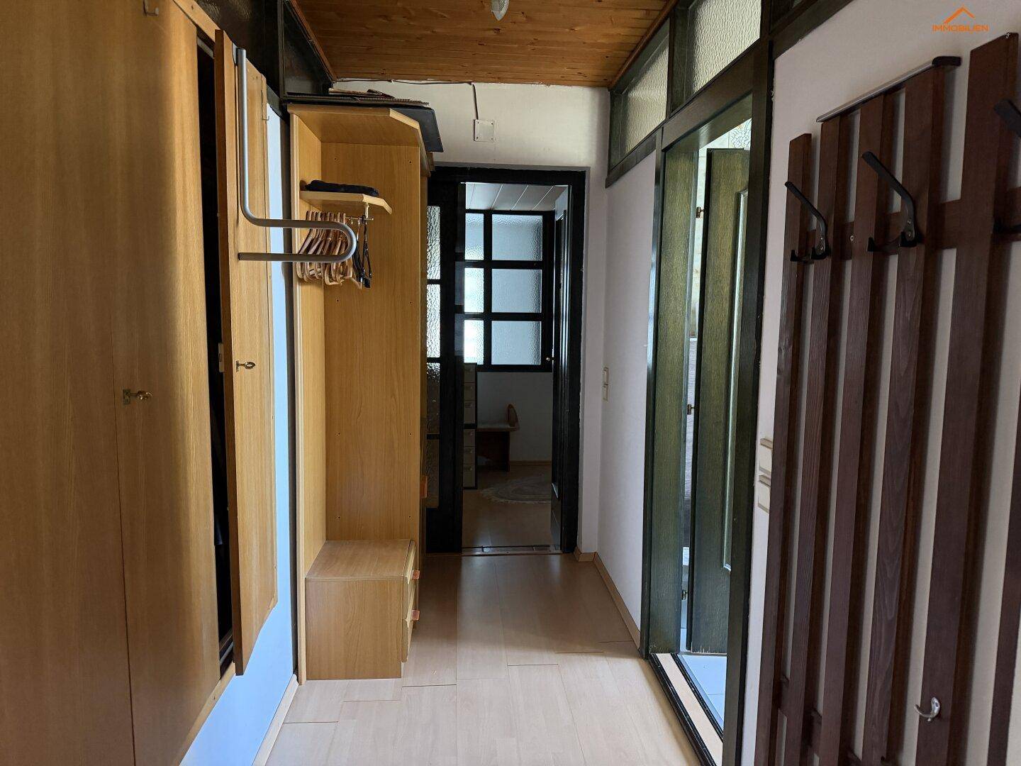 Flur mit Holzboden, Garderobe und integrierten Schränken für Stauraum.