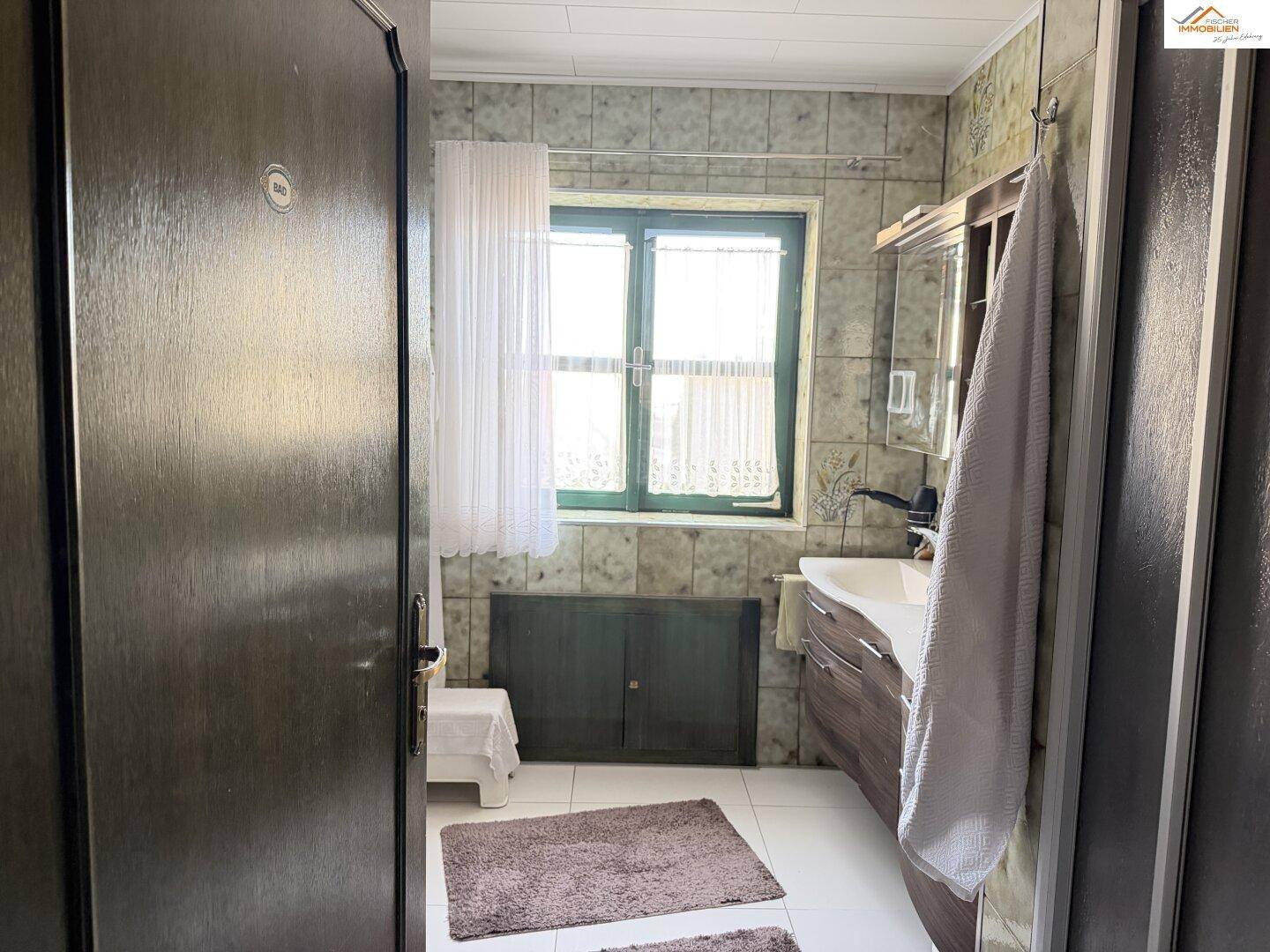 Kleiner Flurbereich mit Holzboden, Fenster und Kommode.