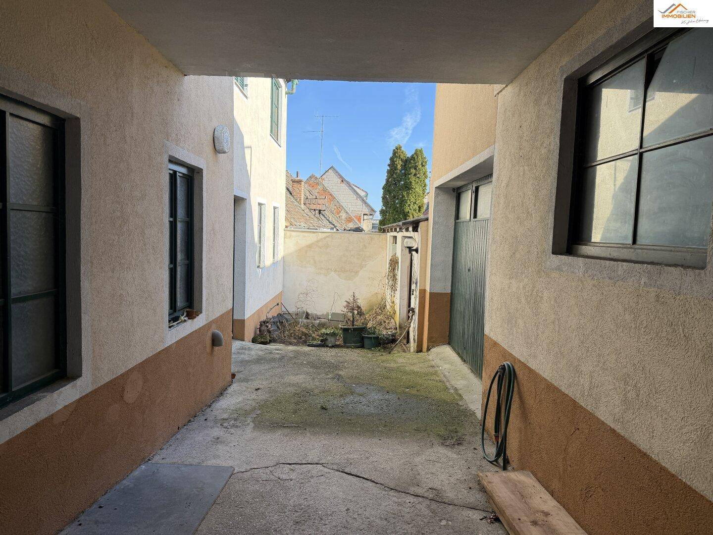 Schmaler Hinterhof zwischen Gebäuden mit Betonboden und einfacher Gestaltung.