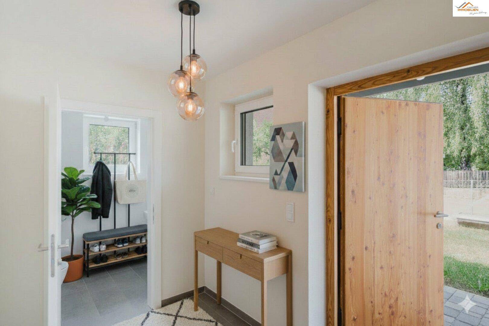 Heller Eingangsbereich mit Holzboden, moderner Pendelleuchte und Garderobe.