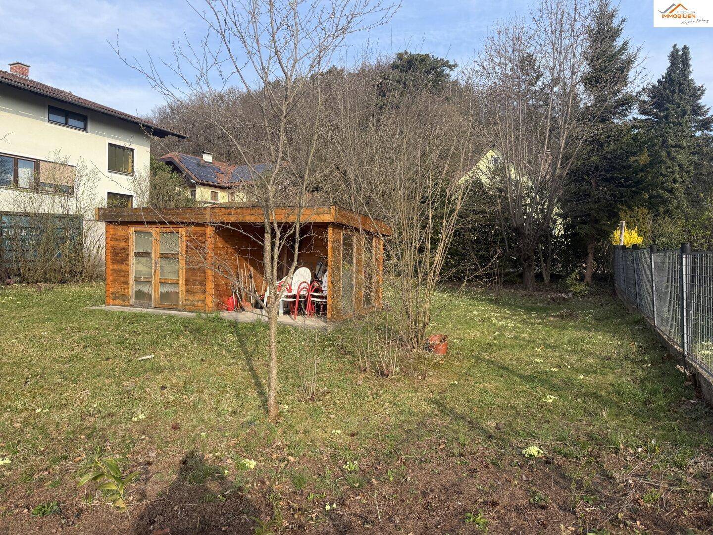 Gartenbereich mit Holzschuppen, umzäuntem Grundstück und angrenzendem Nachbarhaus.
