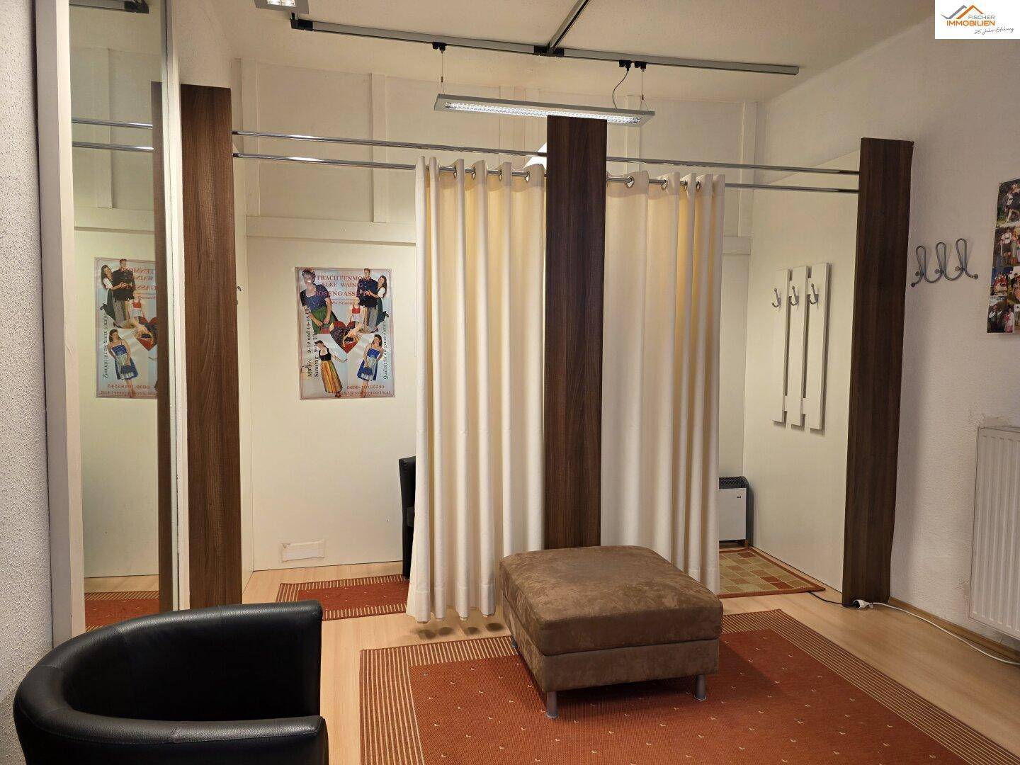 Umkleidebereich mit Vorhängen, einem Hocker und einem Spiegel, ideal für Kunden.
