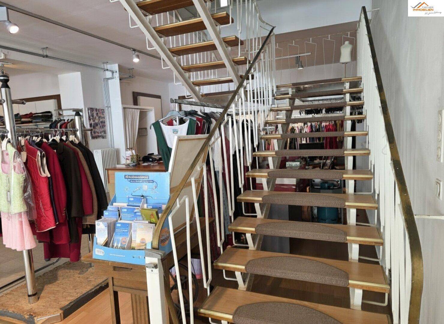 Holztreppe mit Metallgeländer, die in das Obergeschoss des Geschäfts führt.