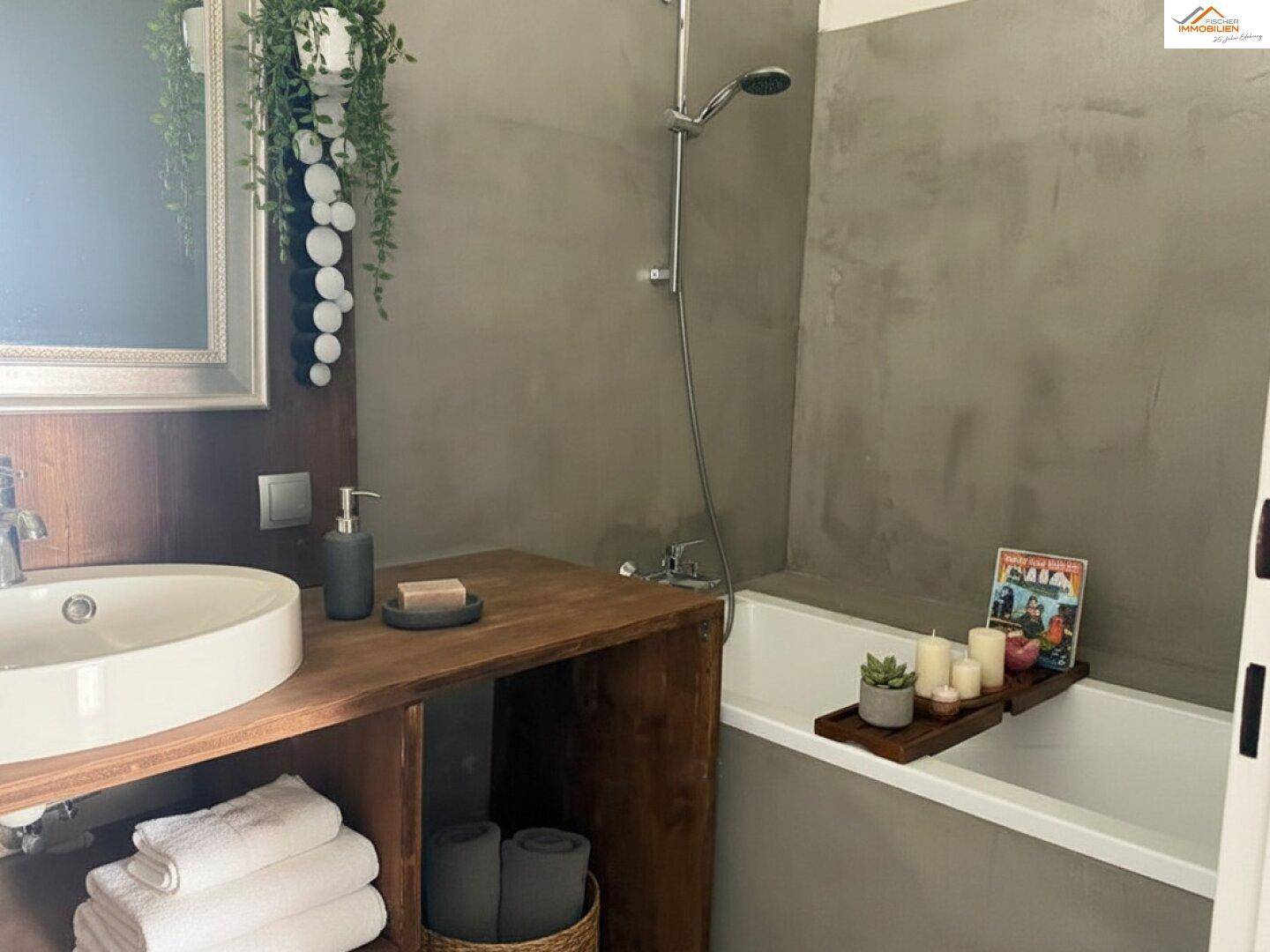 Modernes Badezimmer mit runder Waschschale, Holzunterschrank und Badewanne mit grauen Wänden.