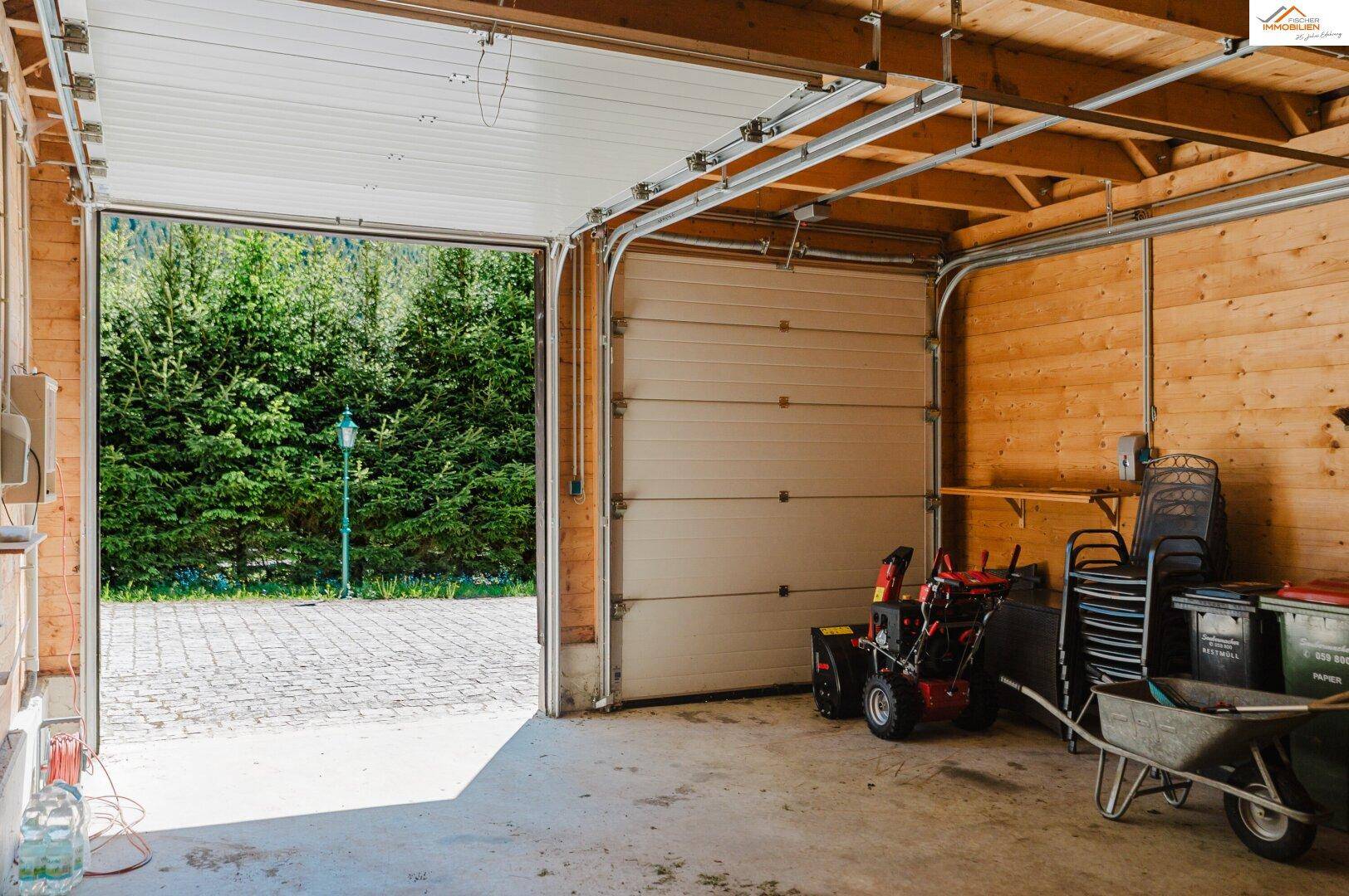 Geräumige Garage mit offenem Tor, Holzverkleidung und Betonboden, bietet Platz für Fahrzeuge und Geräte.