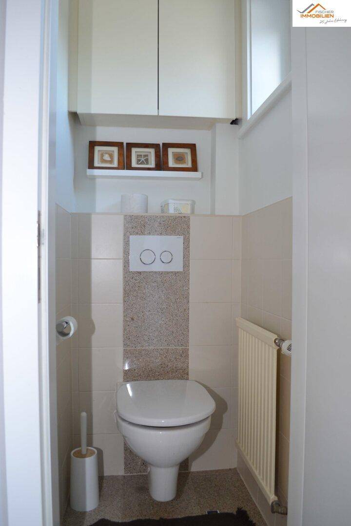 Kleines Gäste-WC mit beigefarbenen Fliesen, Wand-WC und Heizkörper.