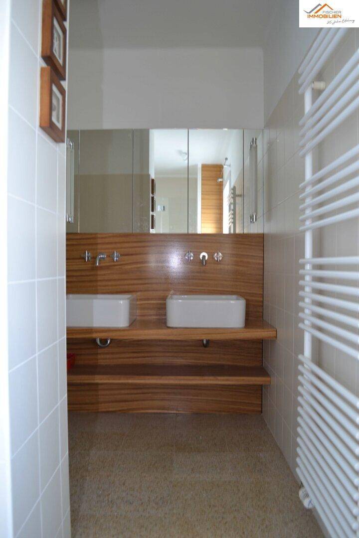 Modernes Badezimmer mit Doppelwaschbecken, Holzverkleidung und großem Spiegelschrank.
