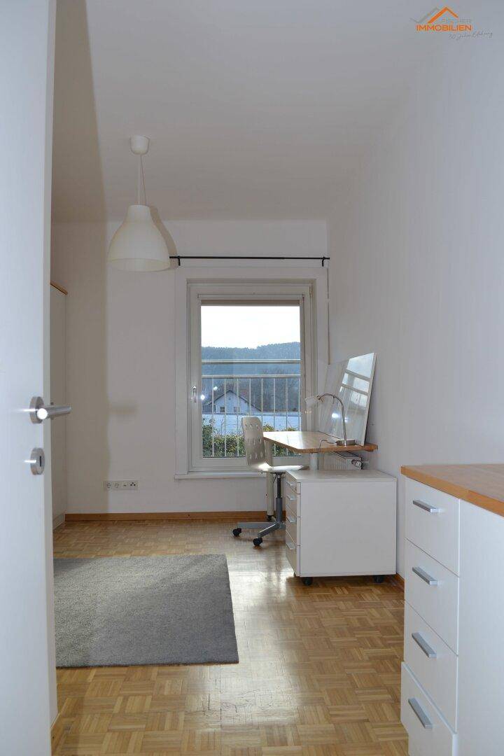 Helles Arbeitszimmer mit Parkettboden, Schreibtisch am Fenster und Blick ins Grüne.