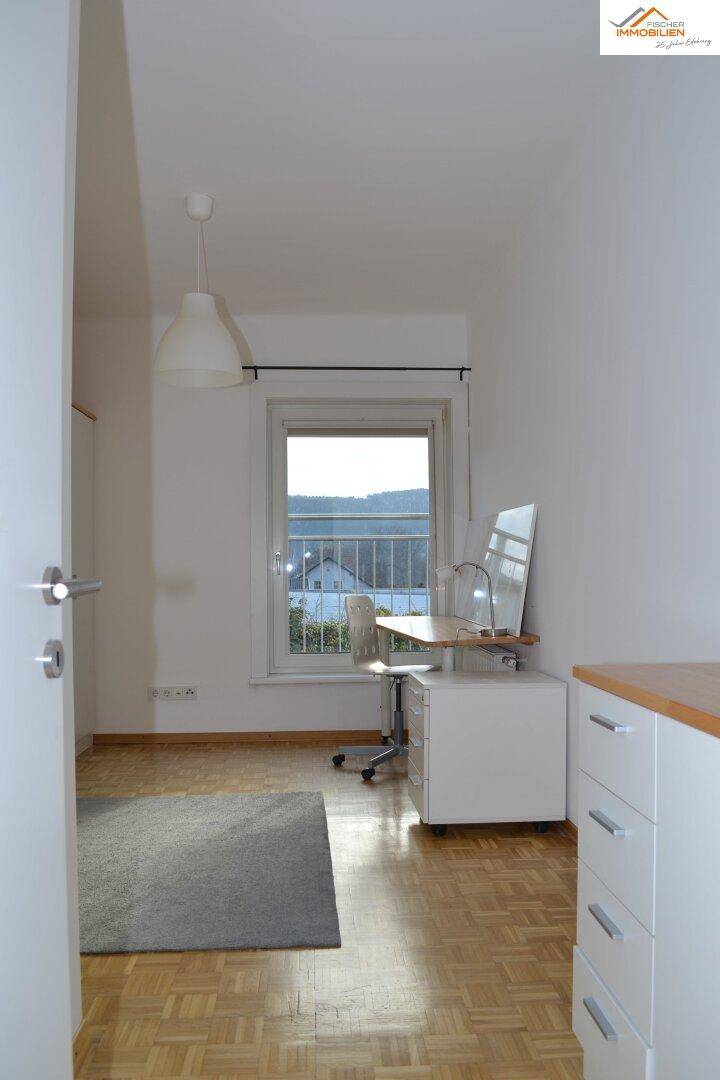 Helles Zimmer mit Parkettboden, Schreibtisch und Blick ins Grüne.