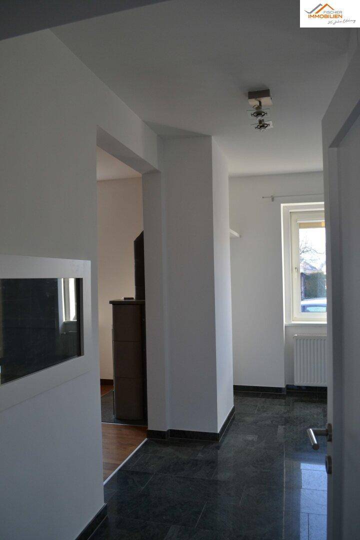 Heller Eingangsbereich mit dunklem Fliesenboden und Blick in angrenzende Räume.