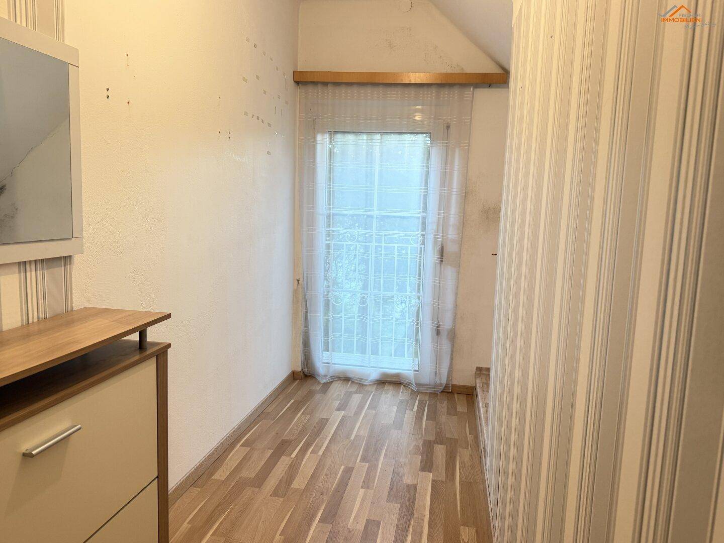 Kleiner Raum mit Laminatboden, Fenster und gestreifter Tapete.