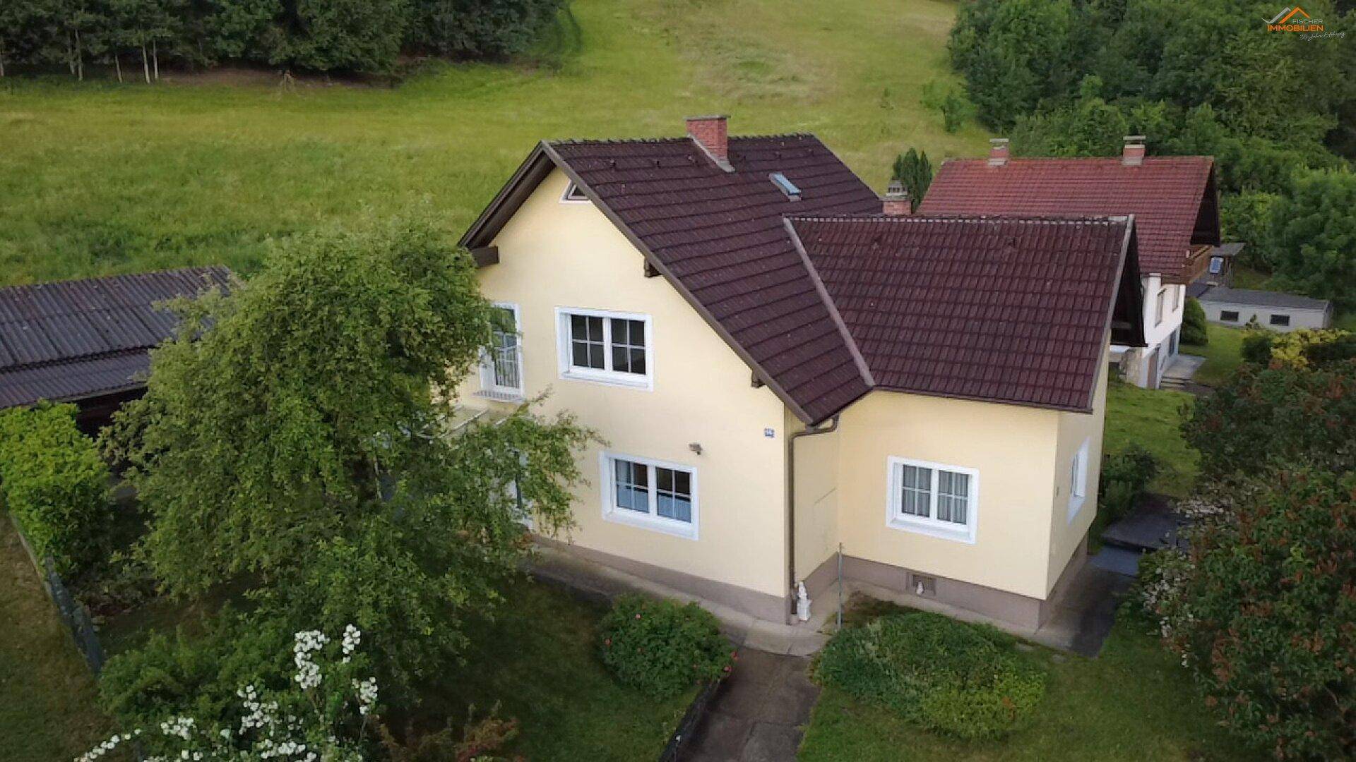 Luftaufnahme eines Einfamilienhauses mit Garten und angrenzenden Feldern.