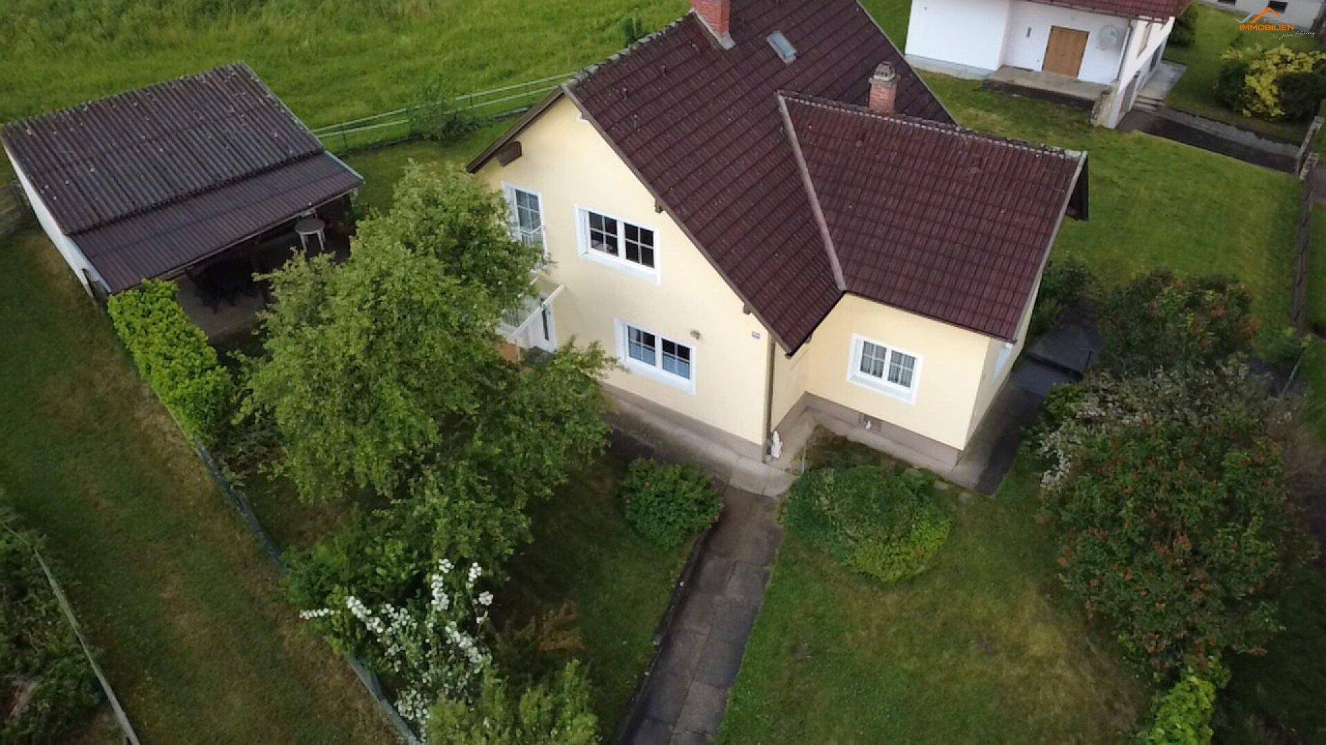 Vogelperspektive des Hauses mit Carport und weitläufigem Gartenbereich.