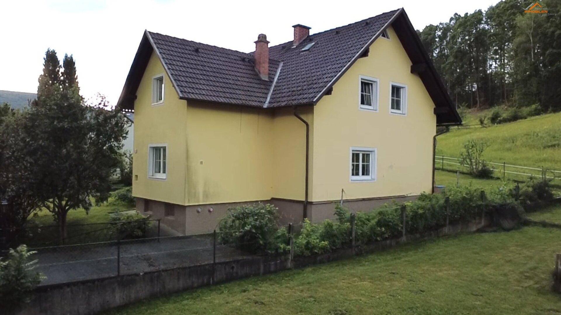 Seitenansicht des Einfamilienhauses mit Garten und Blick auf die Umgebung.