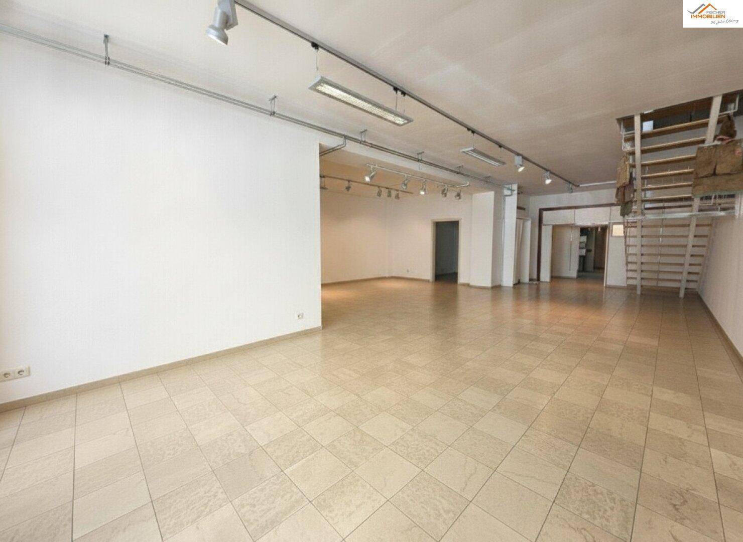 Geräumiger, leerer Raum mit Fliesenboden und Zugang zu weiteren Bereichen.