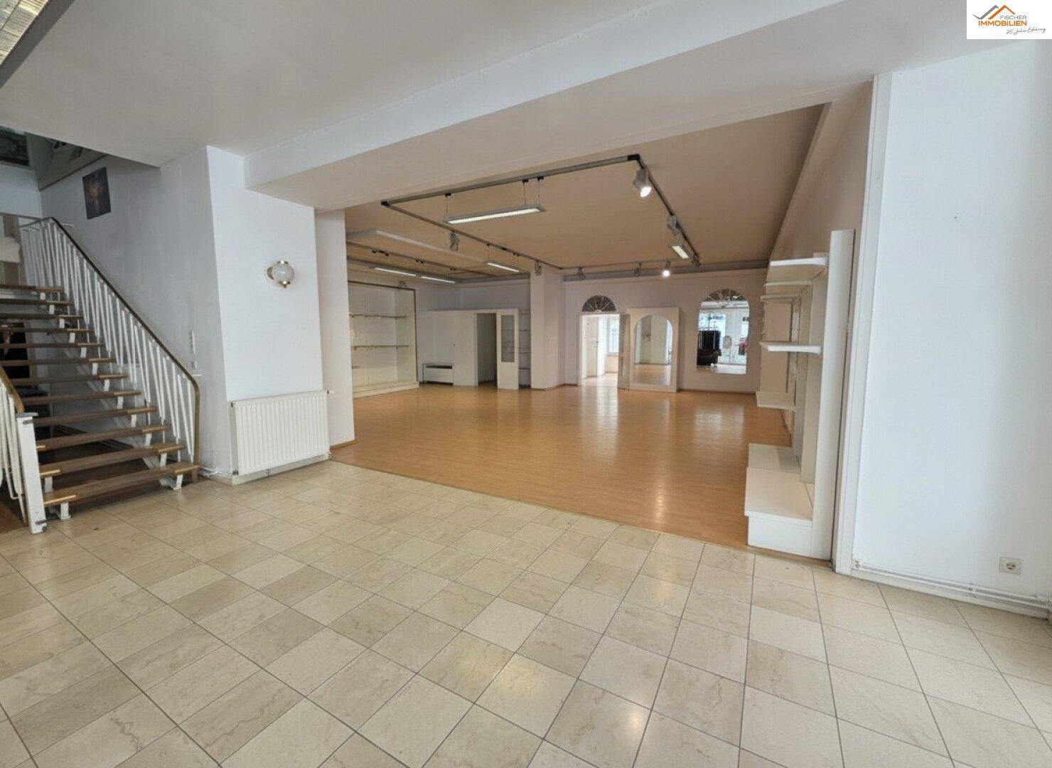 Großer, offener Raum mit Fliesenboden, Holzparkett und einer Treppe zum Obergeschoss.