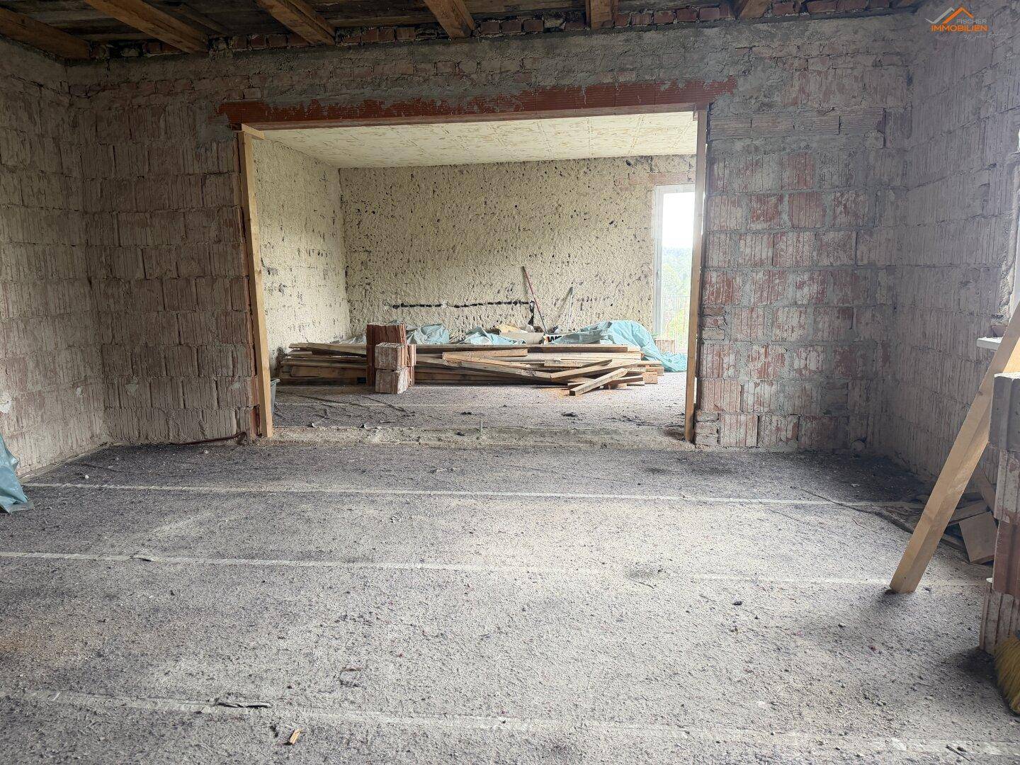 Innenraum im Rohbau mit unverputzten Ziegelwänden und Betonboden, bereit zur Renovierung.