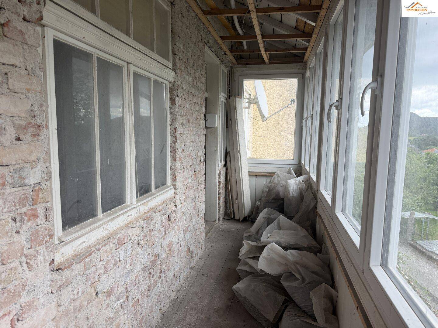 Verglaste Loggia im Rohbau mit Ziegelwänden und Blick auf die Umgebung, bereit zur Fertigstellung.