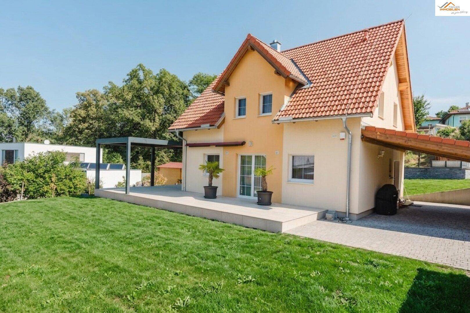Ansicht des Einfamilienhauses mit gepflegtem Vorgarten, Terrasse und Carport.