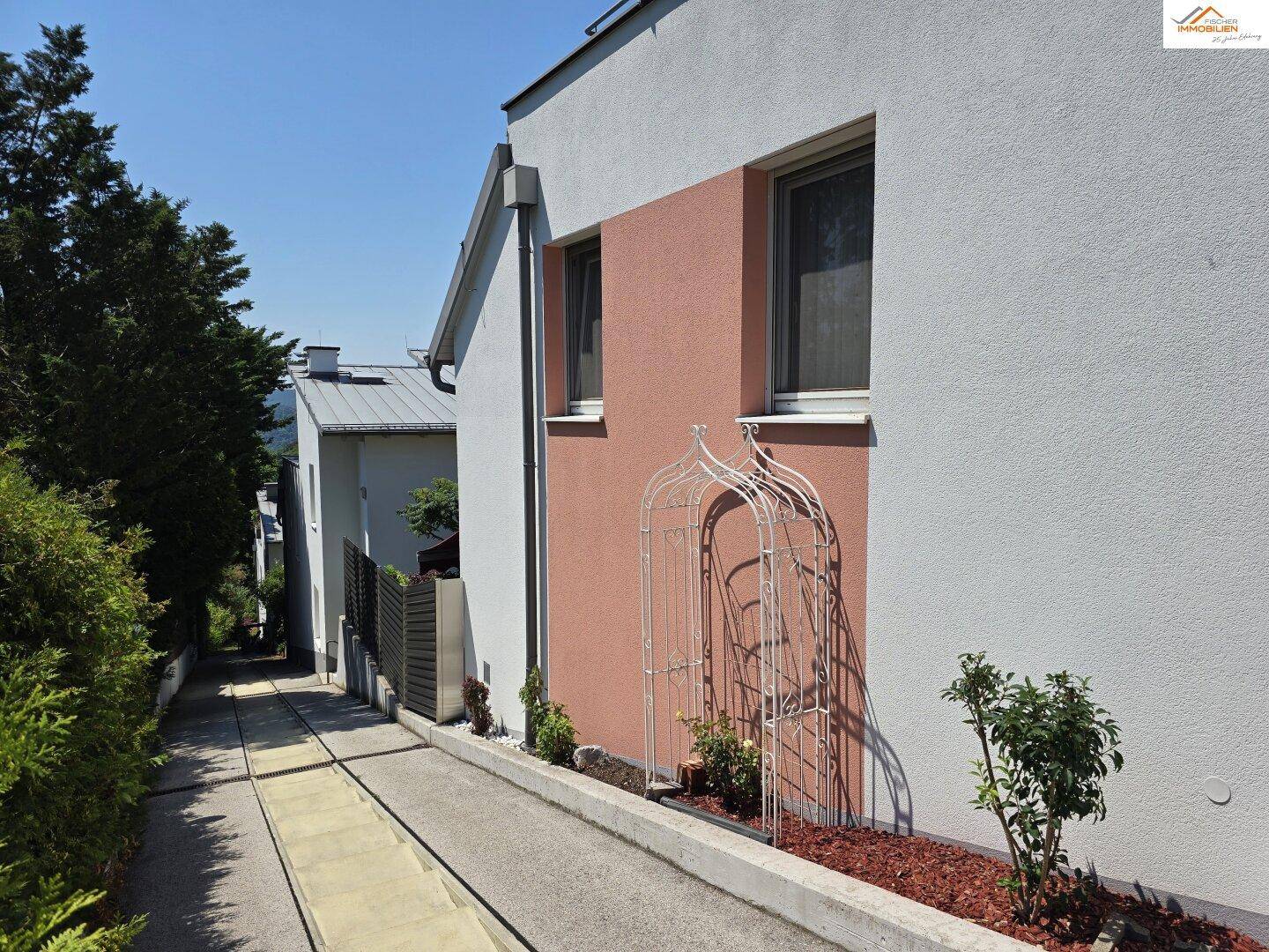 Seitenansicht des Hauses mit Zufahrt und gepflegter Bepflanzung entlang der Fassade.