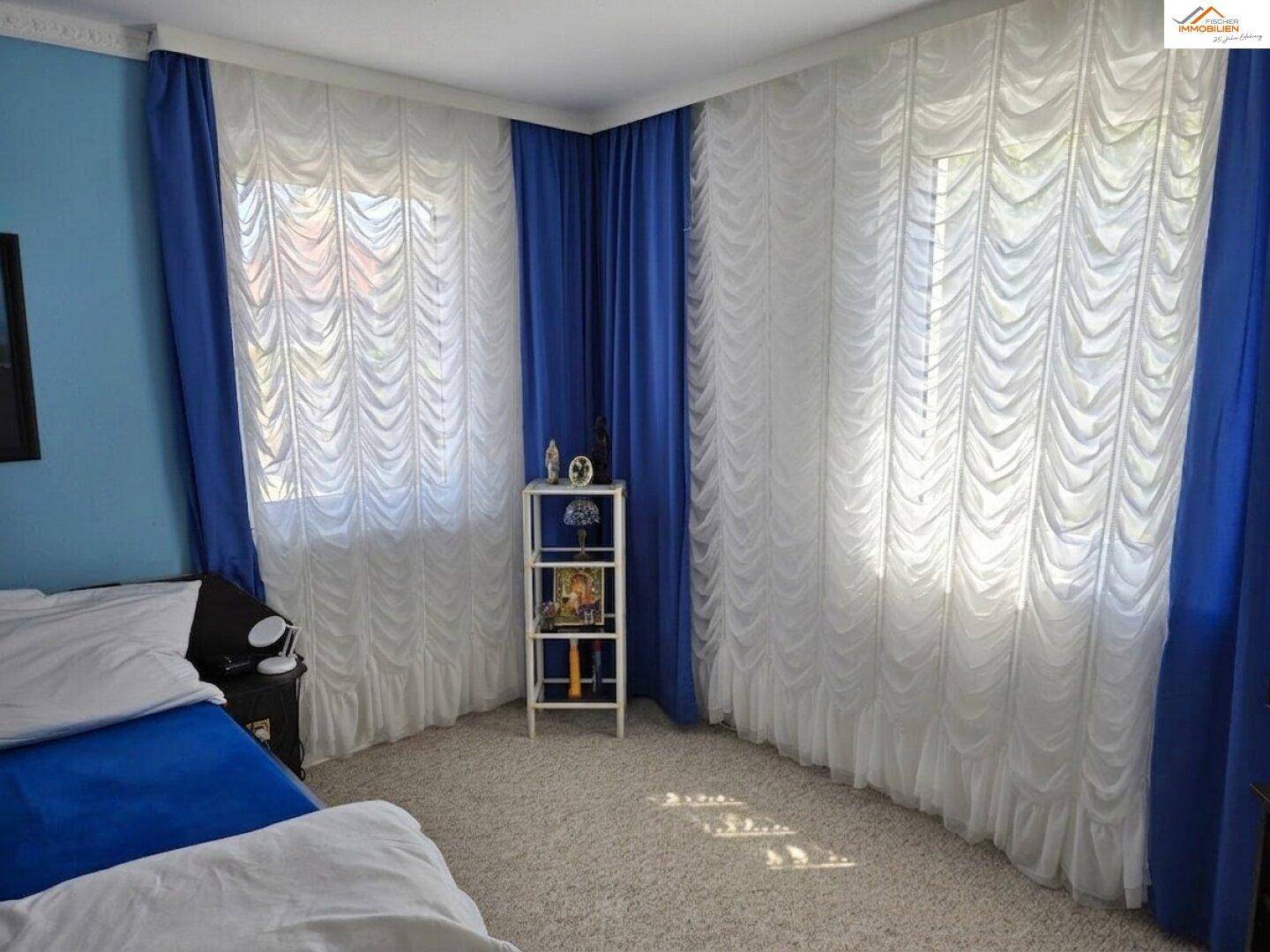 Schlafzimmer mit blauen Vorhängen und Teppichboden, bietet eine ruhige und helle Atmosphäre.