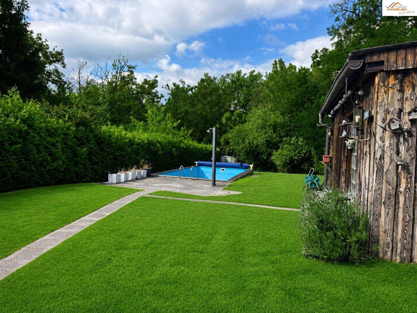 Gepflegter Gartenbereich mit Rasenfläche, kleinem Pool und rustikalem Holzschuppen.