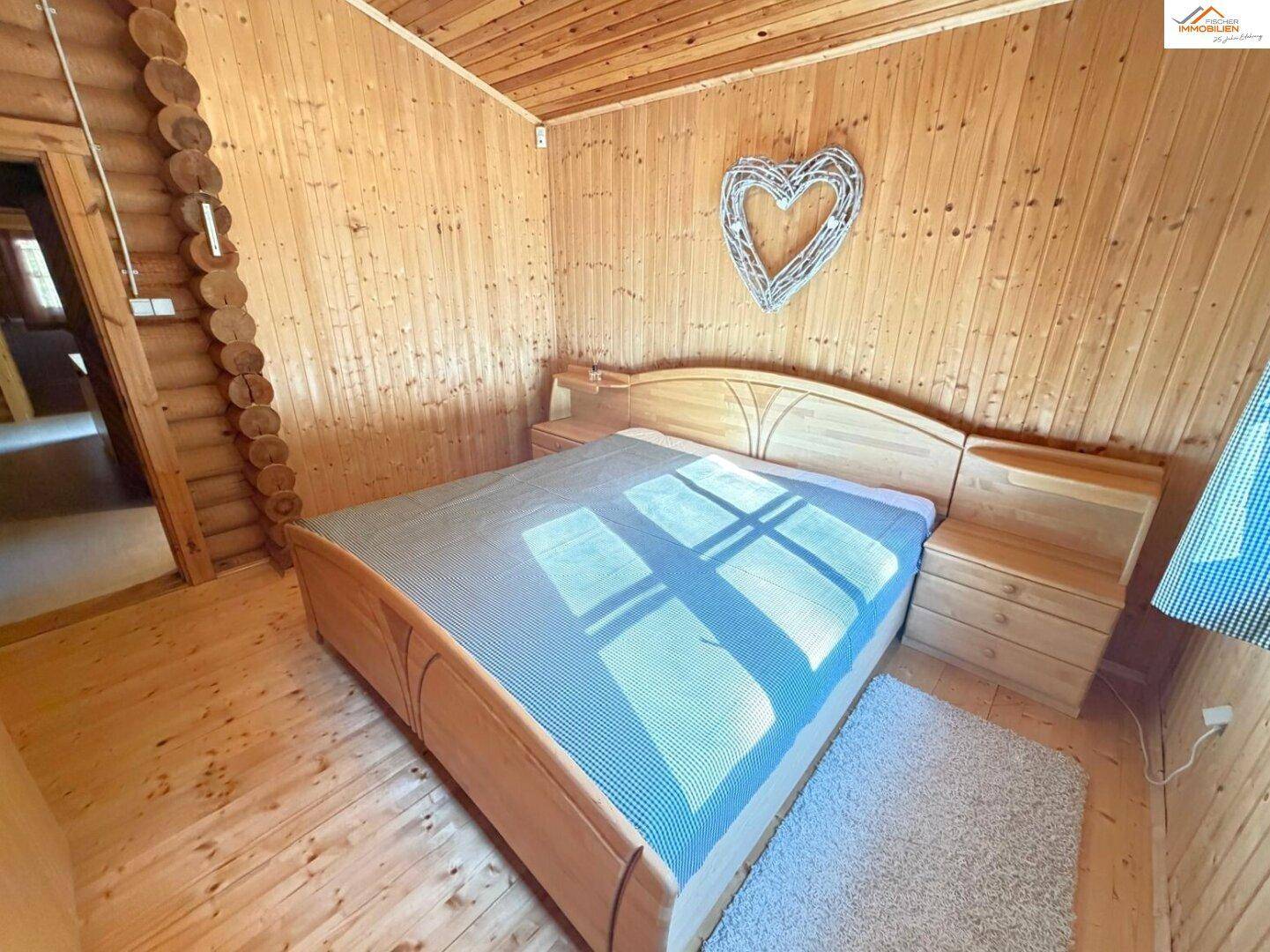 Geräumiges Schlafzimmer im Blockhaus mit Holzboden und -wänden, das eine warme Atmosphäre schafft.