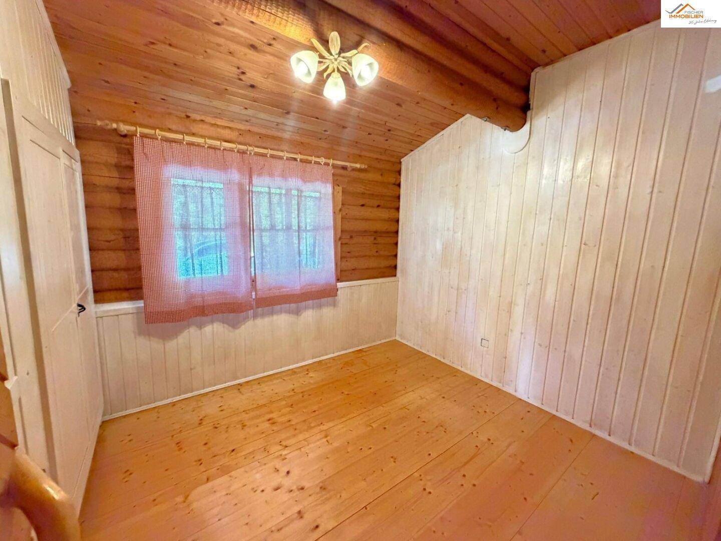 Helles Schlafzimmer mit Holzdielenboden und weiß gestrichenen Holzpaneelen an den Wänden.