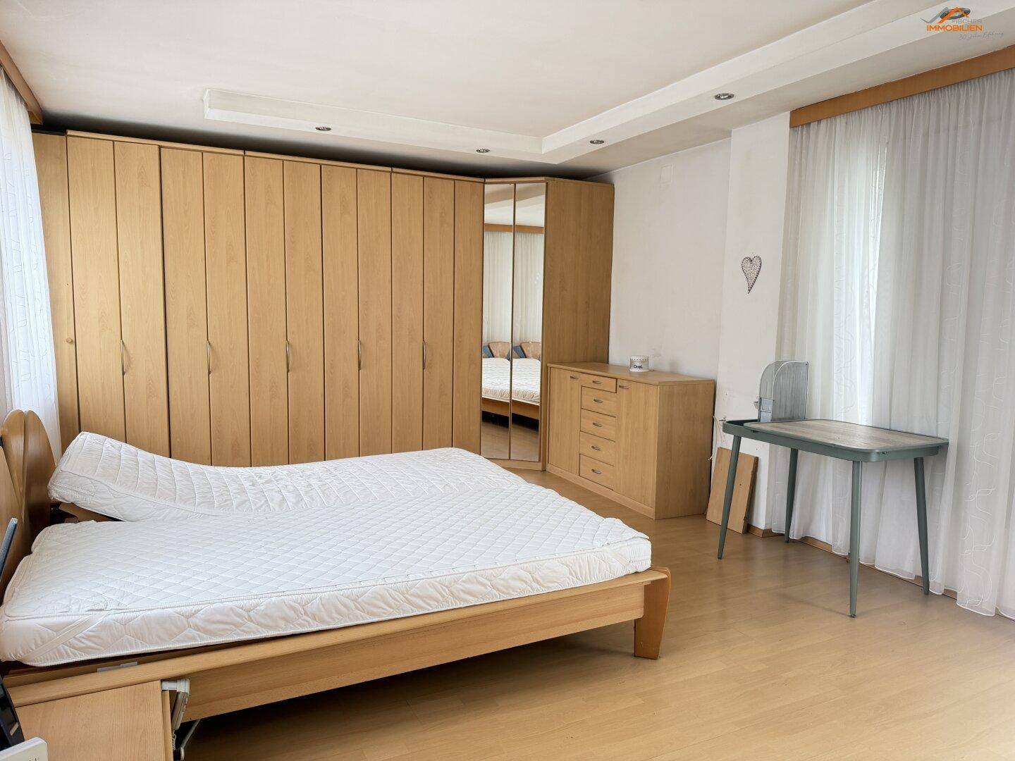 Helles Schlafzimmer mit Holzbett, großen Einbauschränken und Parkettboden.