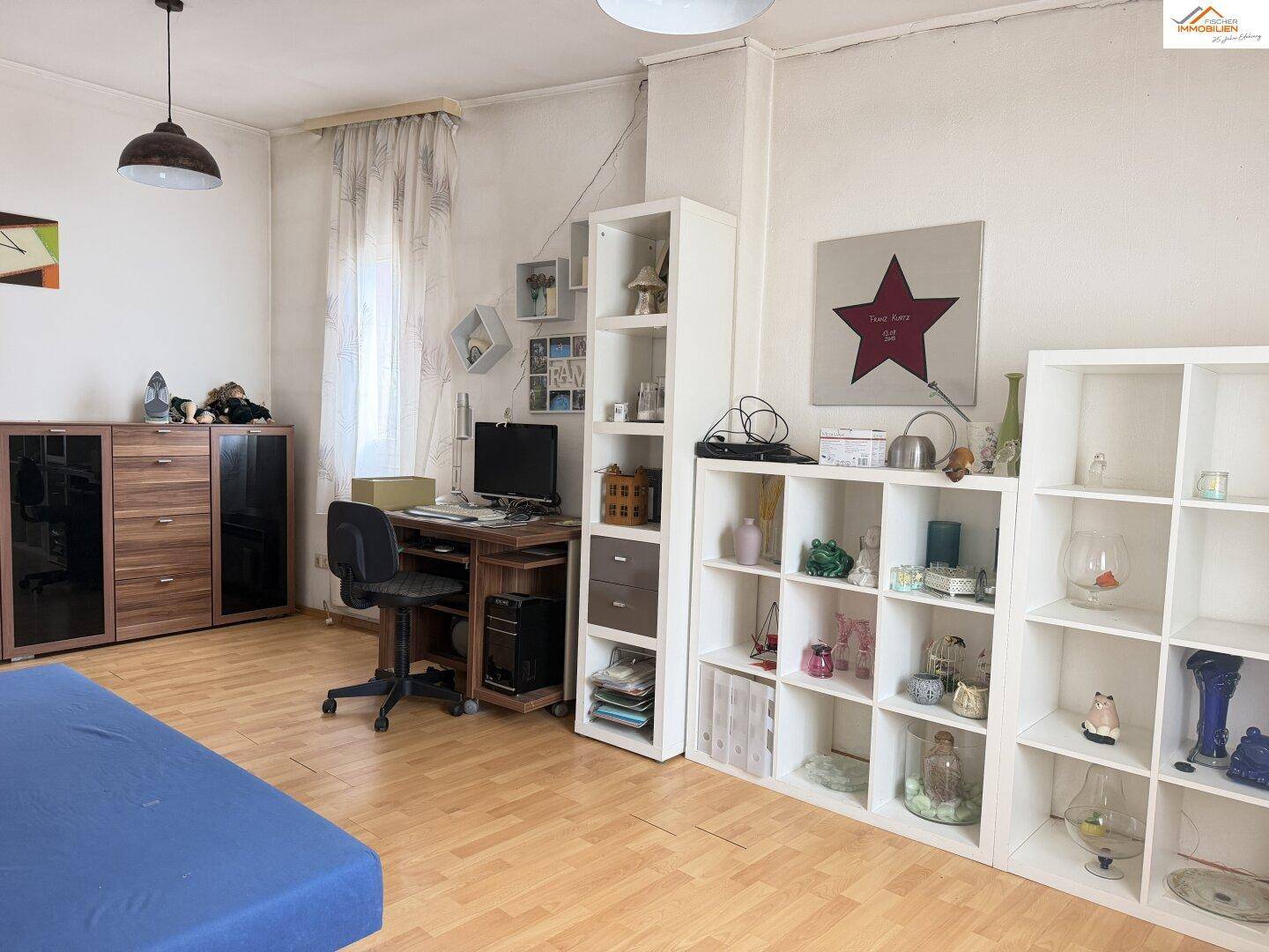 Helles Zimmer mit Bett, Schreibtisch und Regalen, ideal als Kinder- oder Gästezimmer.