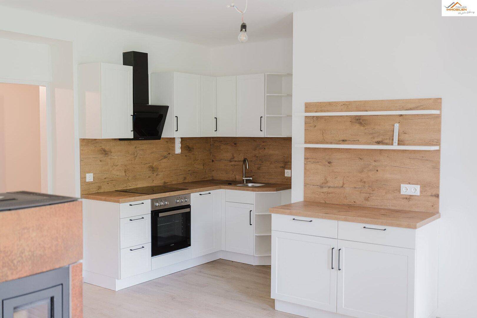 Moderne Einbauküche mit weißen Schränken, Holzoptik-Arbeitsplatten und integrierten Geräten.