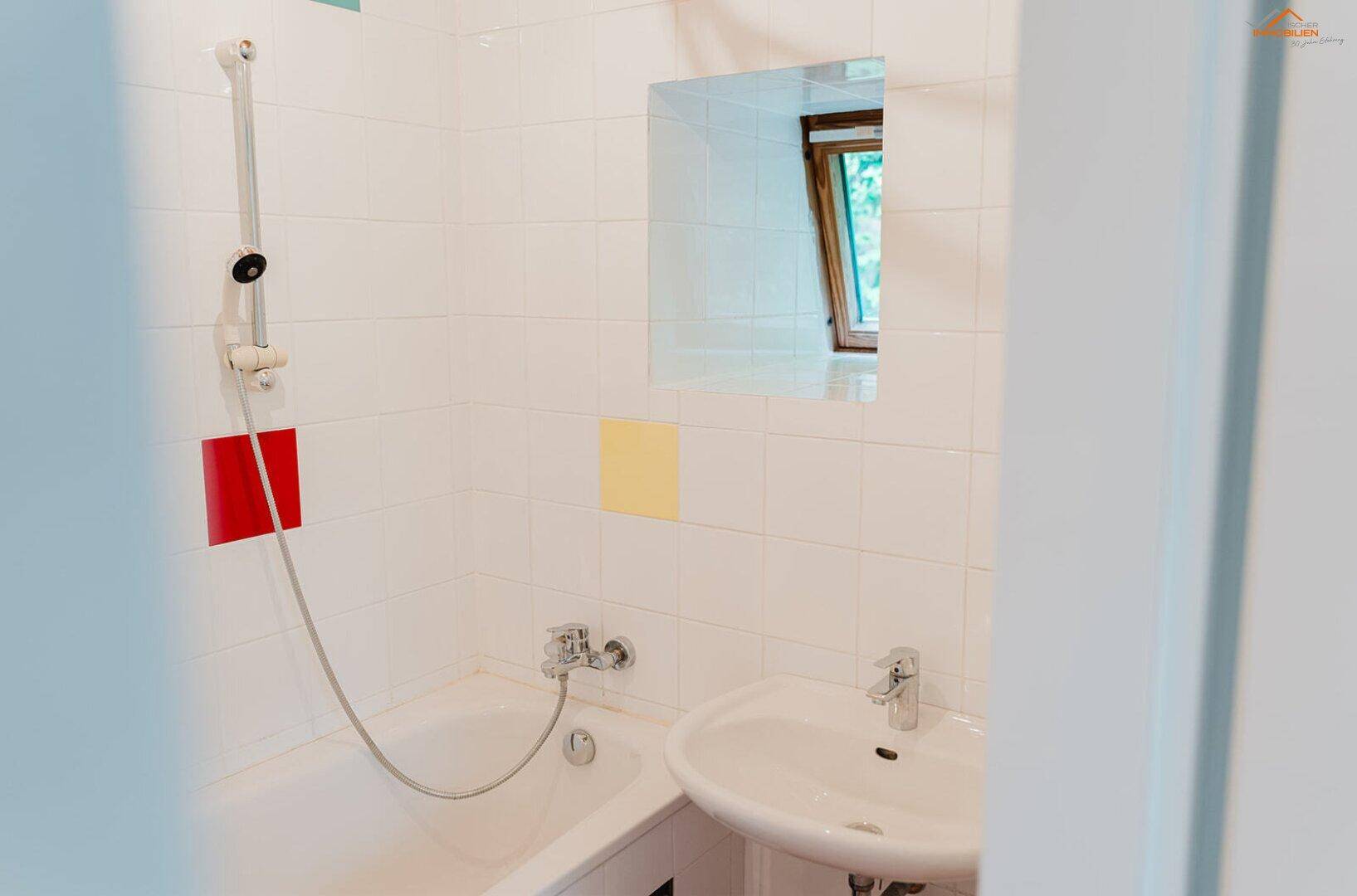 Badezimmer mit Badewanne, Waschbecken und Dachfenster, das Tageslicht hereinlässt.